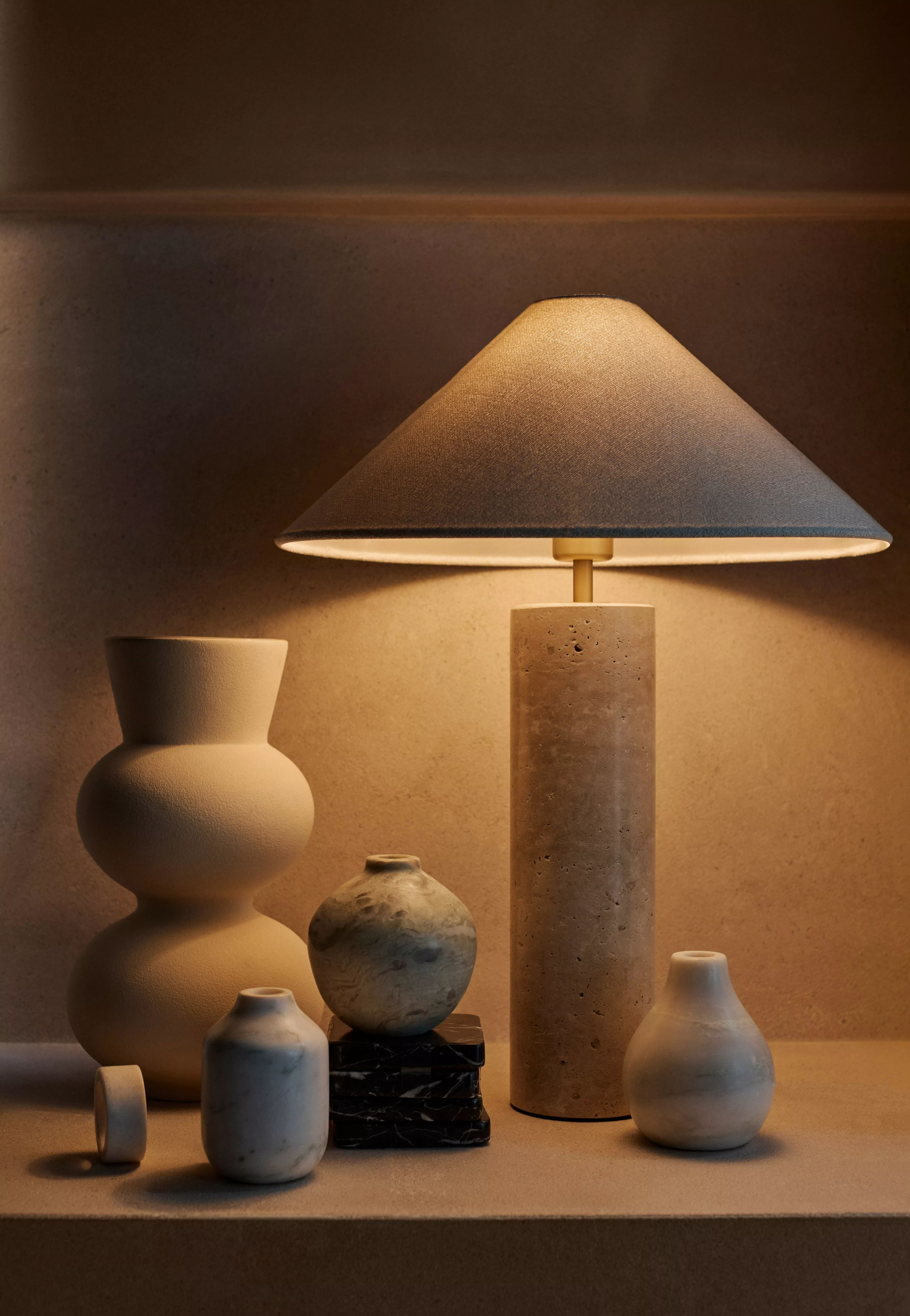 A table lamp with a white shade and a green glass cieling pendant
