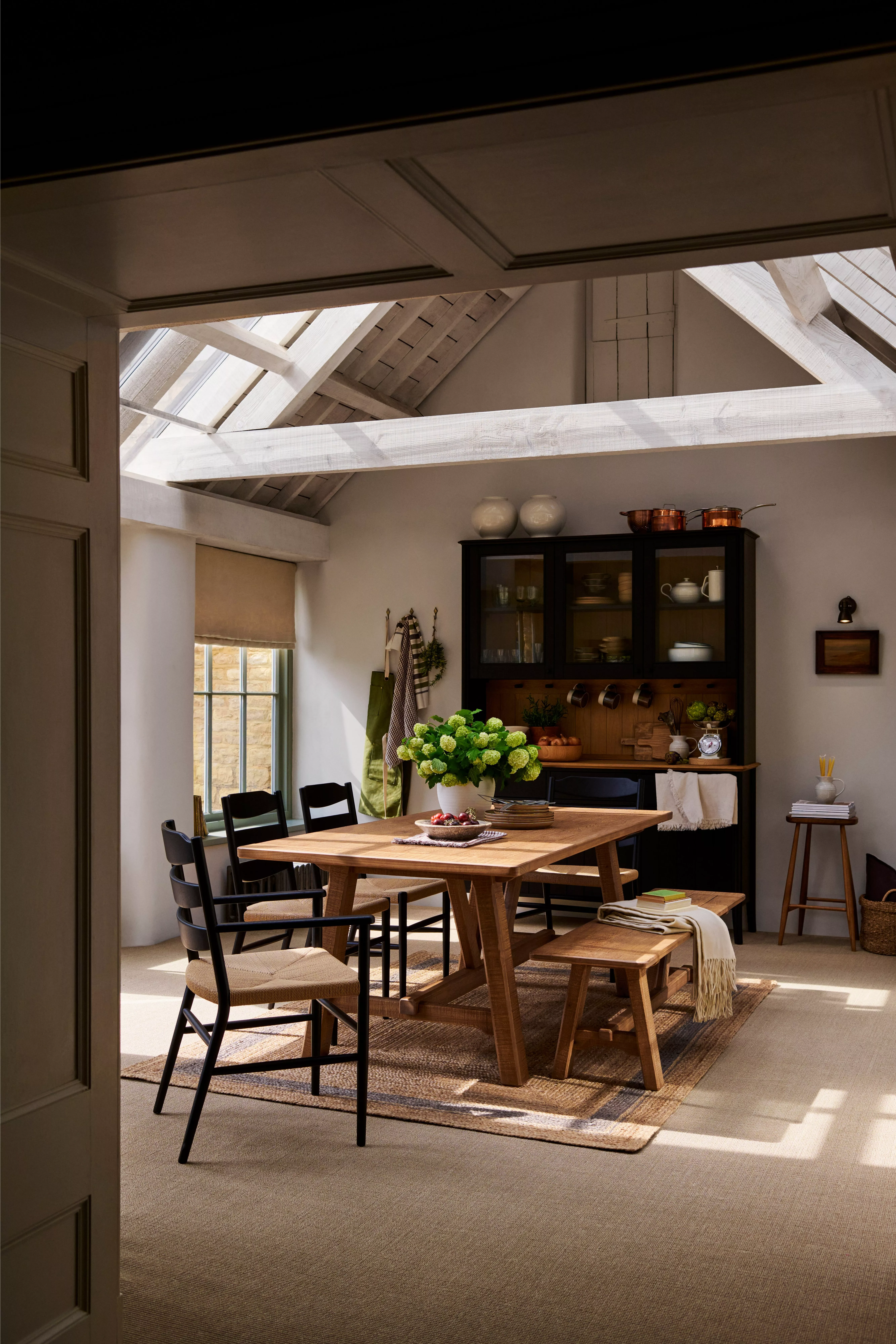 Wooden dining table with a bench and black chairs with wicker seat pads