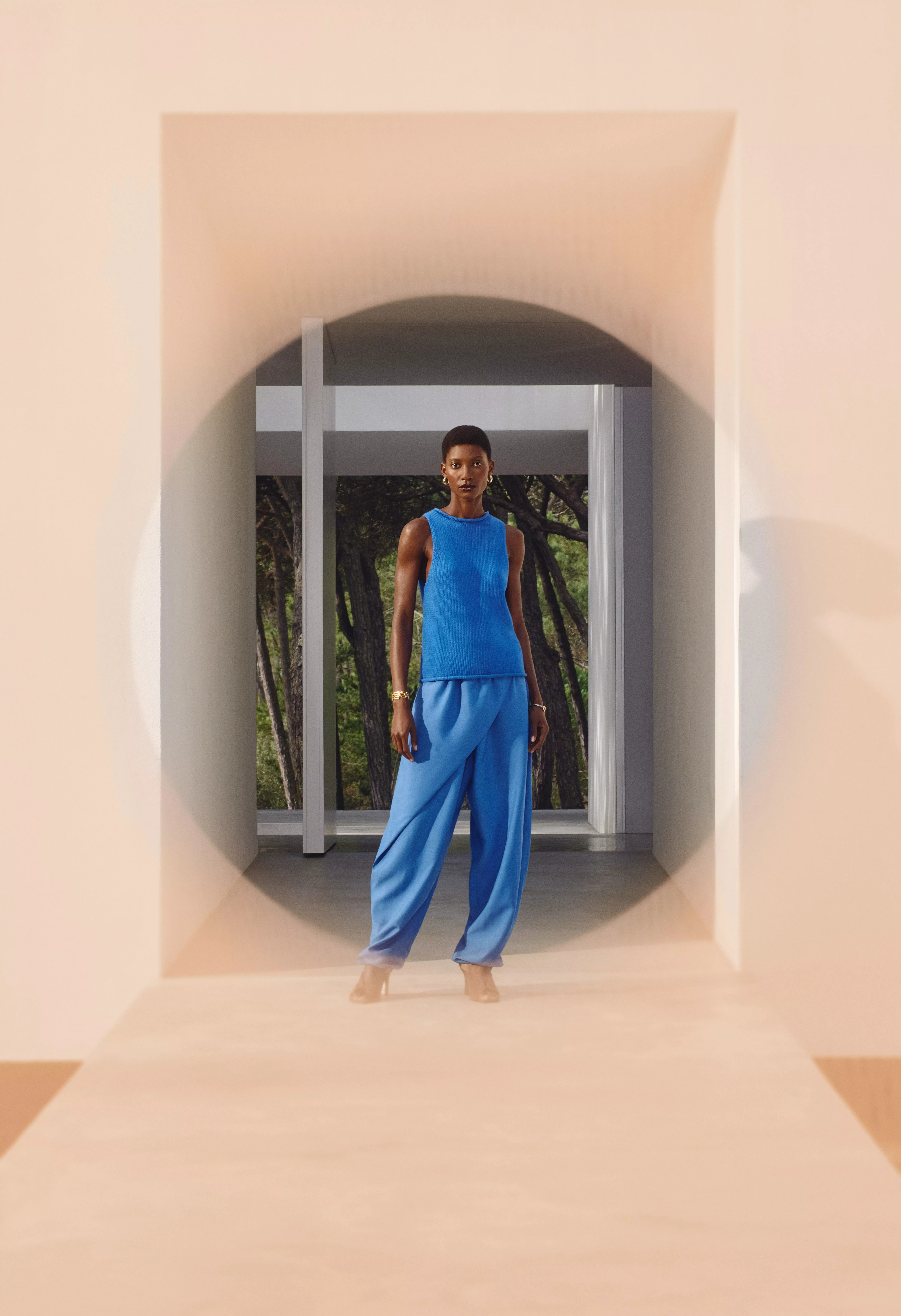 Person wearing a bright blue sleeveless knit top and matching blue trousers