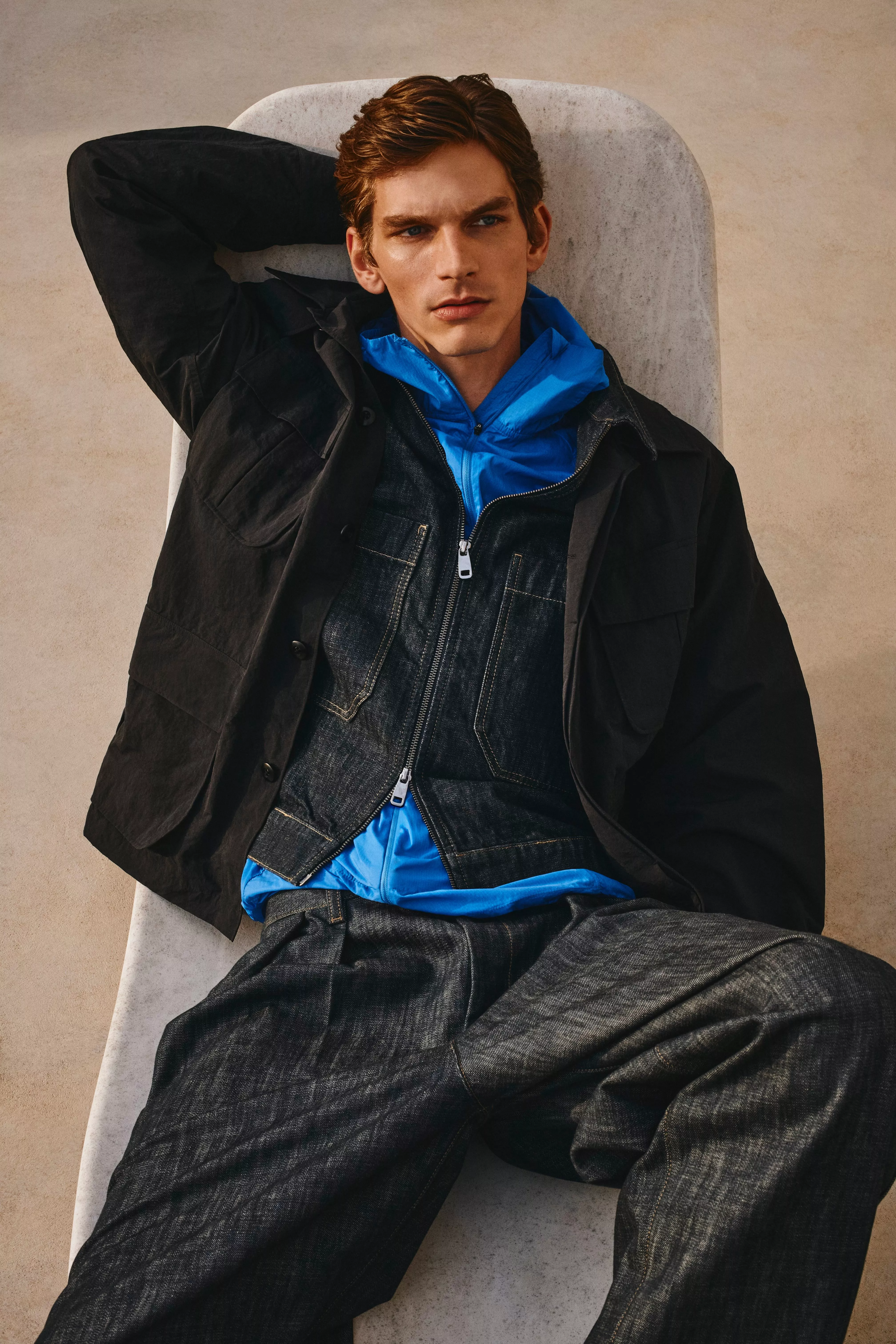 Man wearing dark rinse denim jeans and zip up jacket with black shacket on top