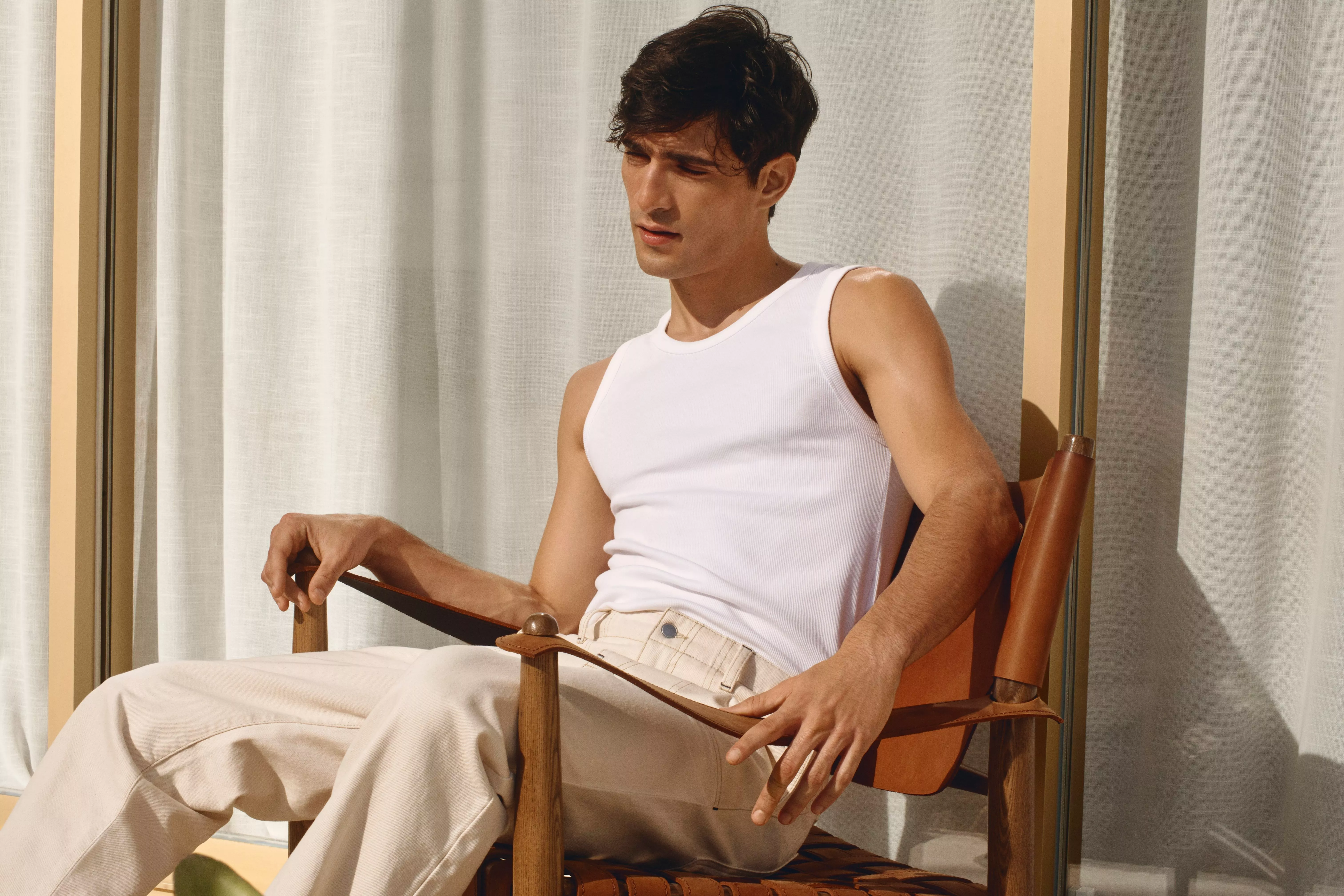 Man wearing a white vest and beige trousers