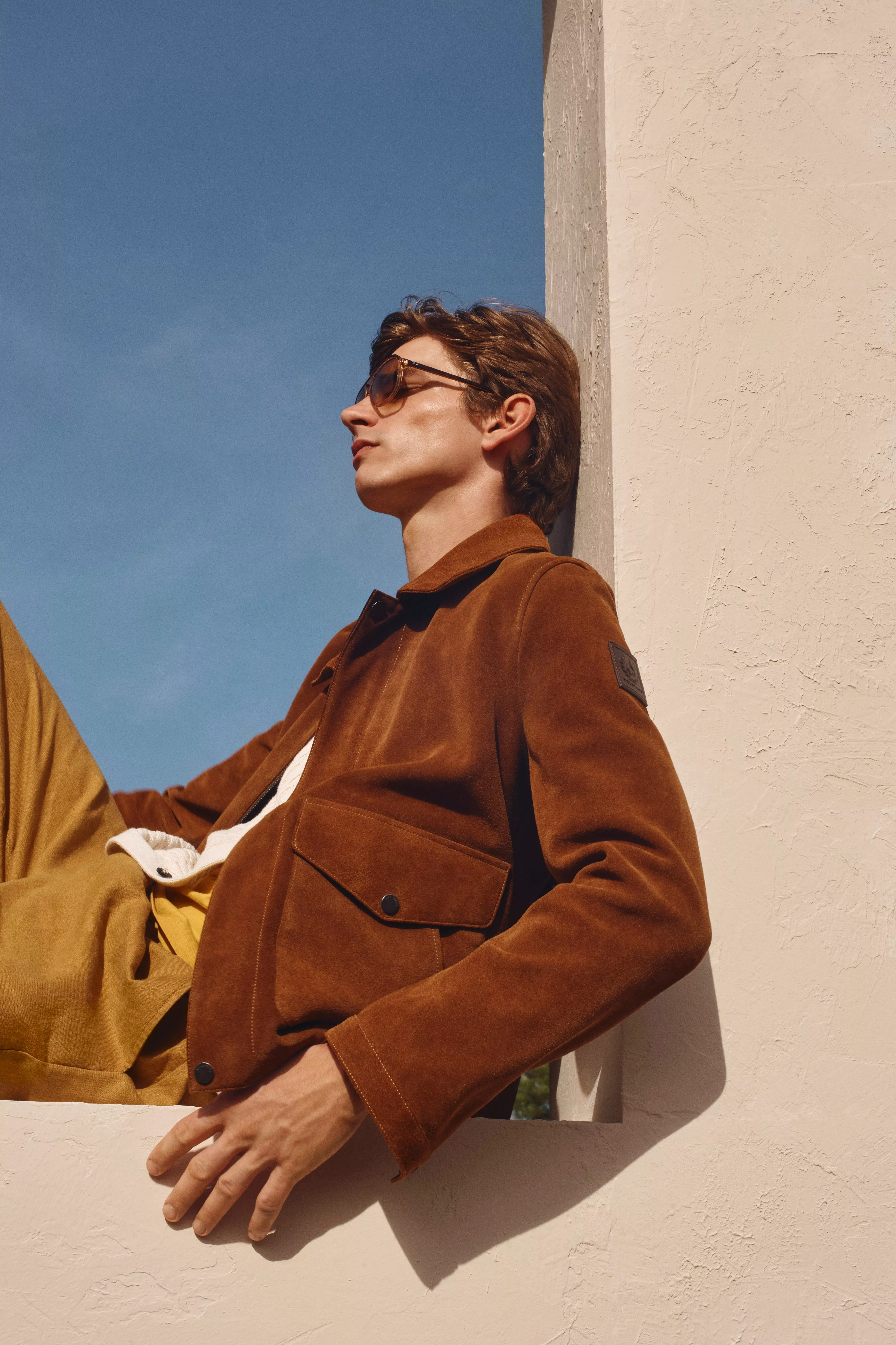 Man wearing a tan suede jacket with mustard coloured trousers