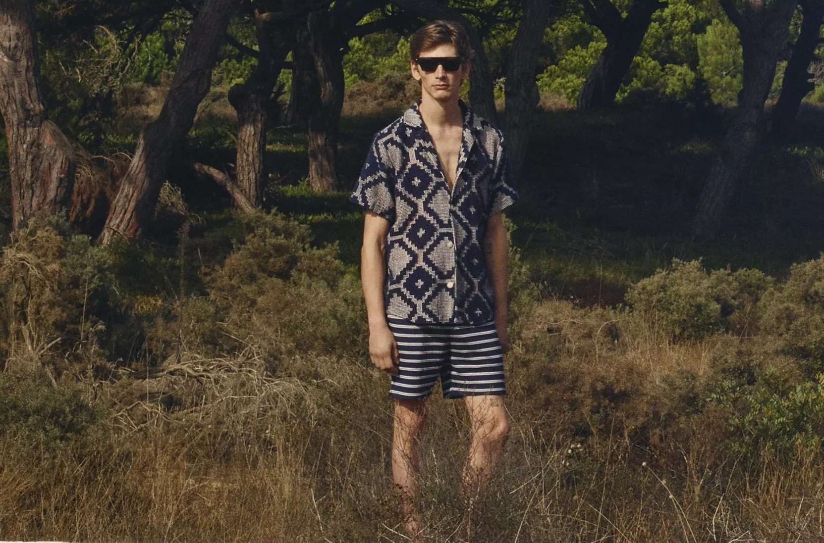 Man wearing a patterned short sleeve shirt and stripe shorts