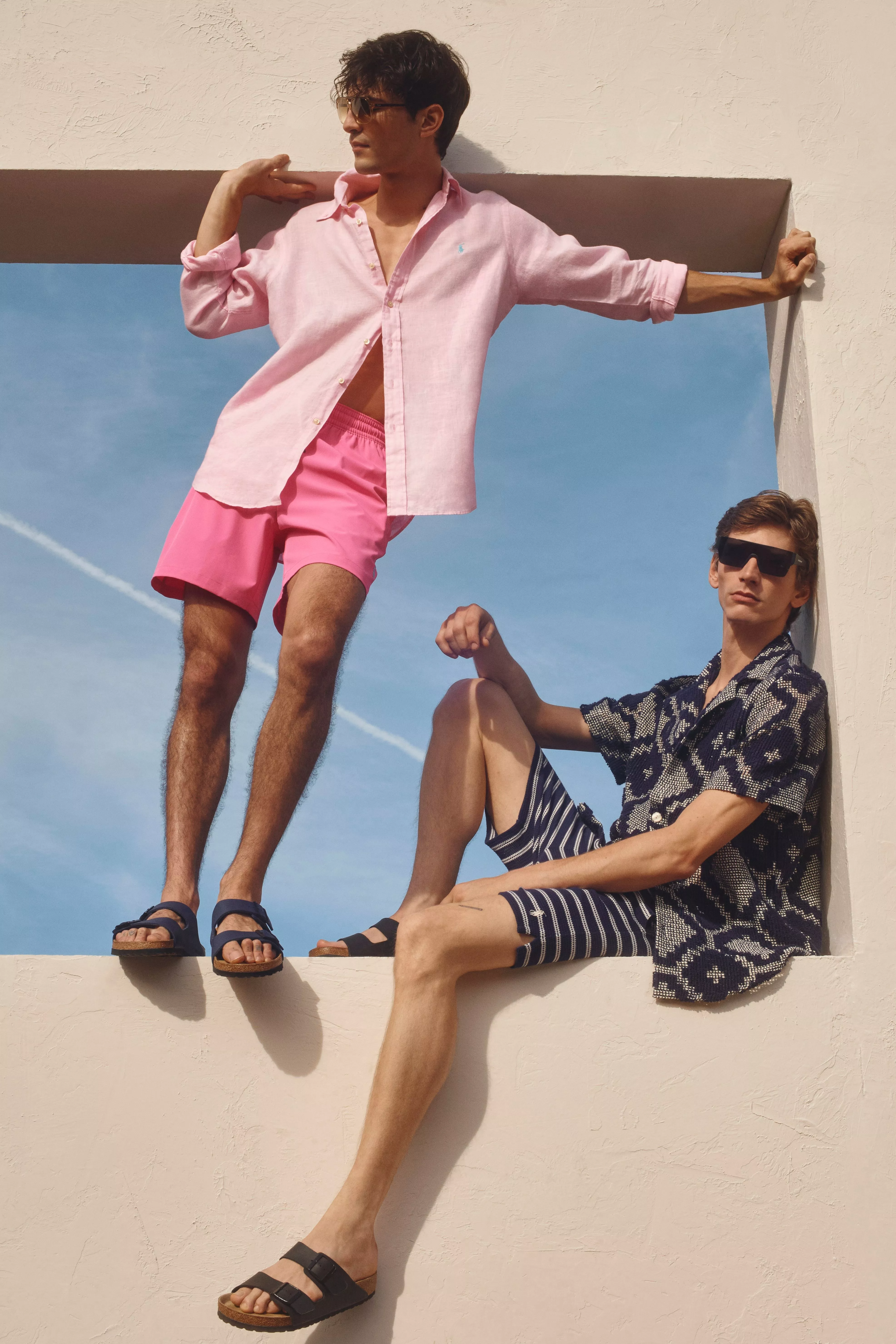 Two men wearing shirts and shorts with open toe sandals 