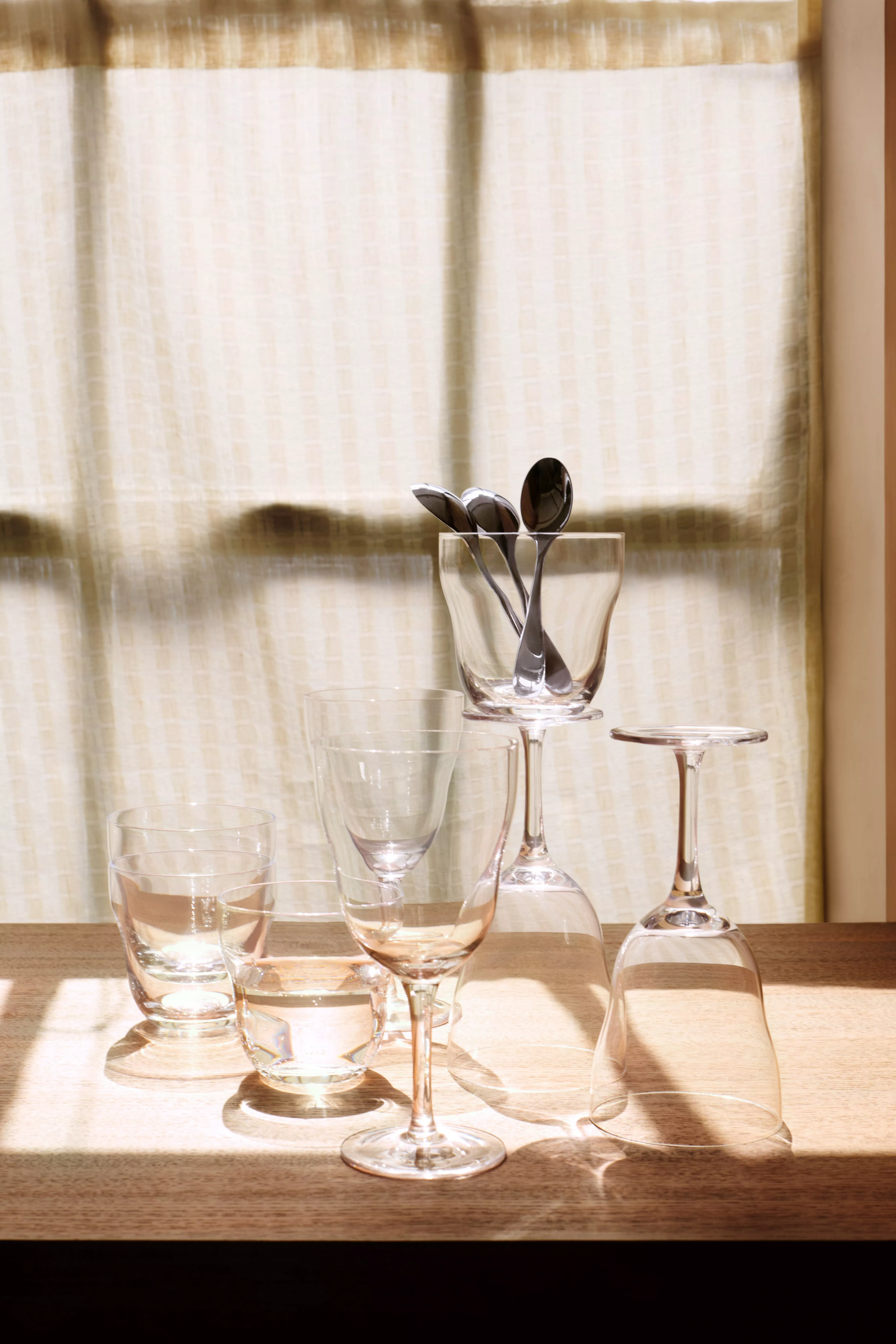 Blue glass goblets and tumblers arranged on a wooden table, modern home décor still life in soft daylight.
