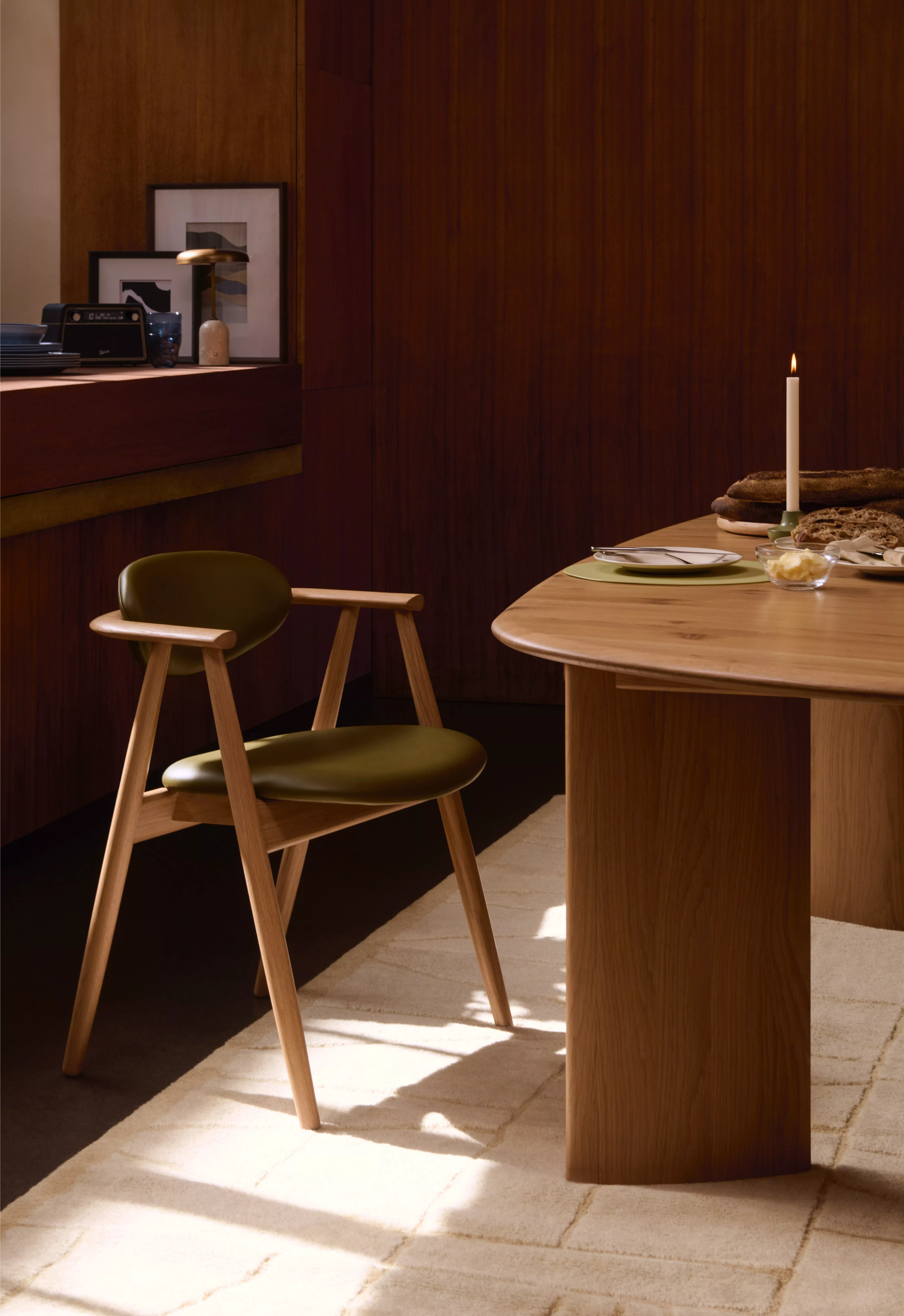 Scandinavian oak dining chair with upholstered seat beside modern table, minimalist bright dining room setting