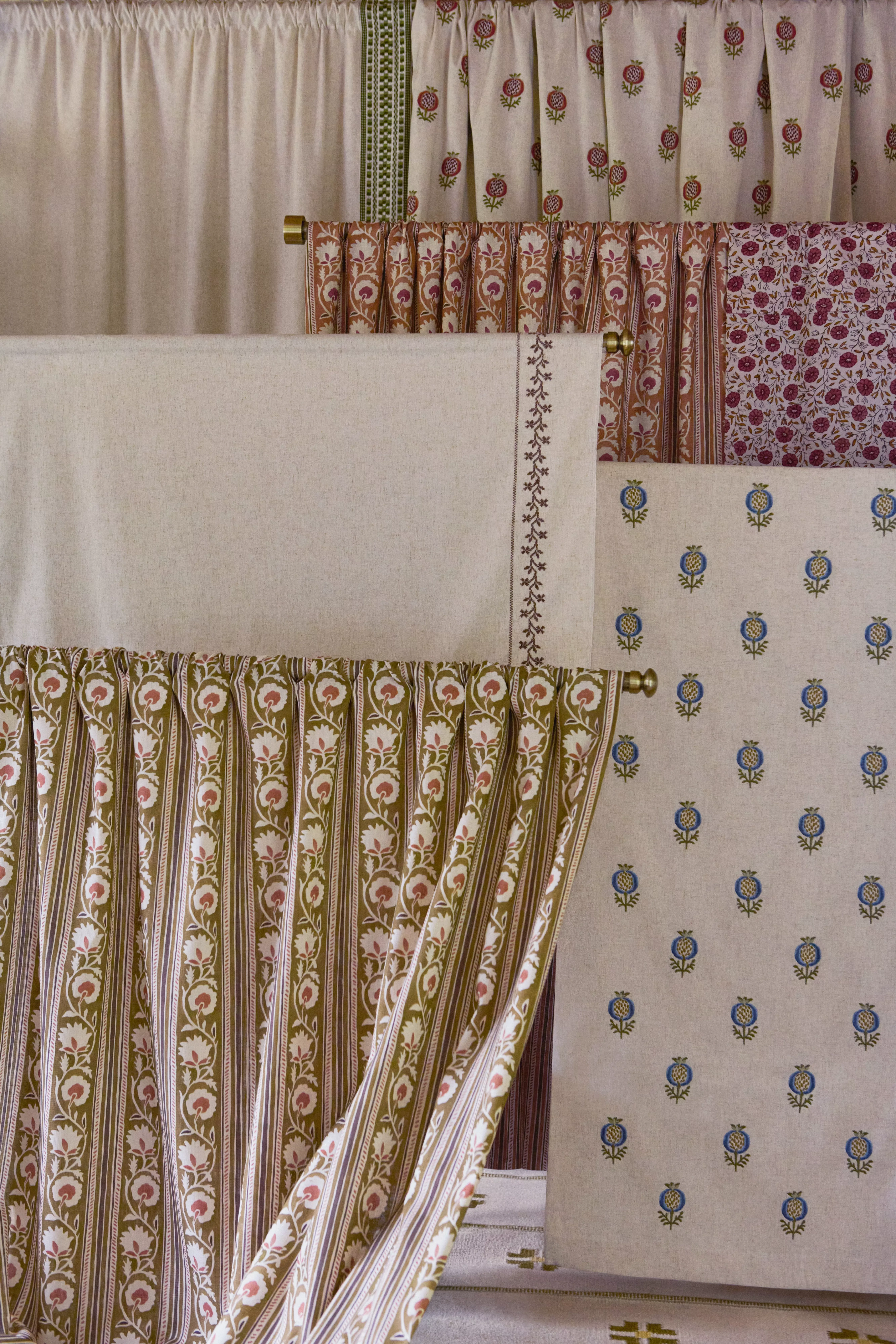 Layered floral and striped cotton curtains and fabric panels in neutral tones, showcasing decorative textile prints
