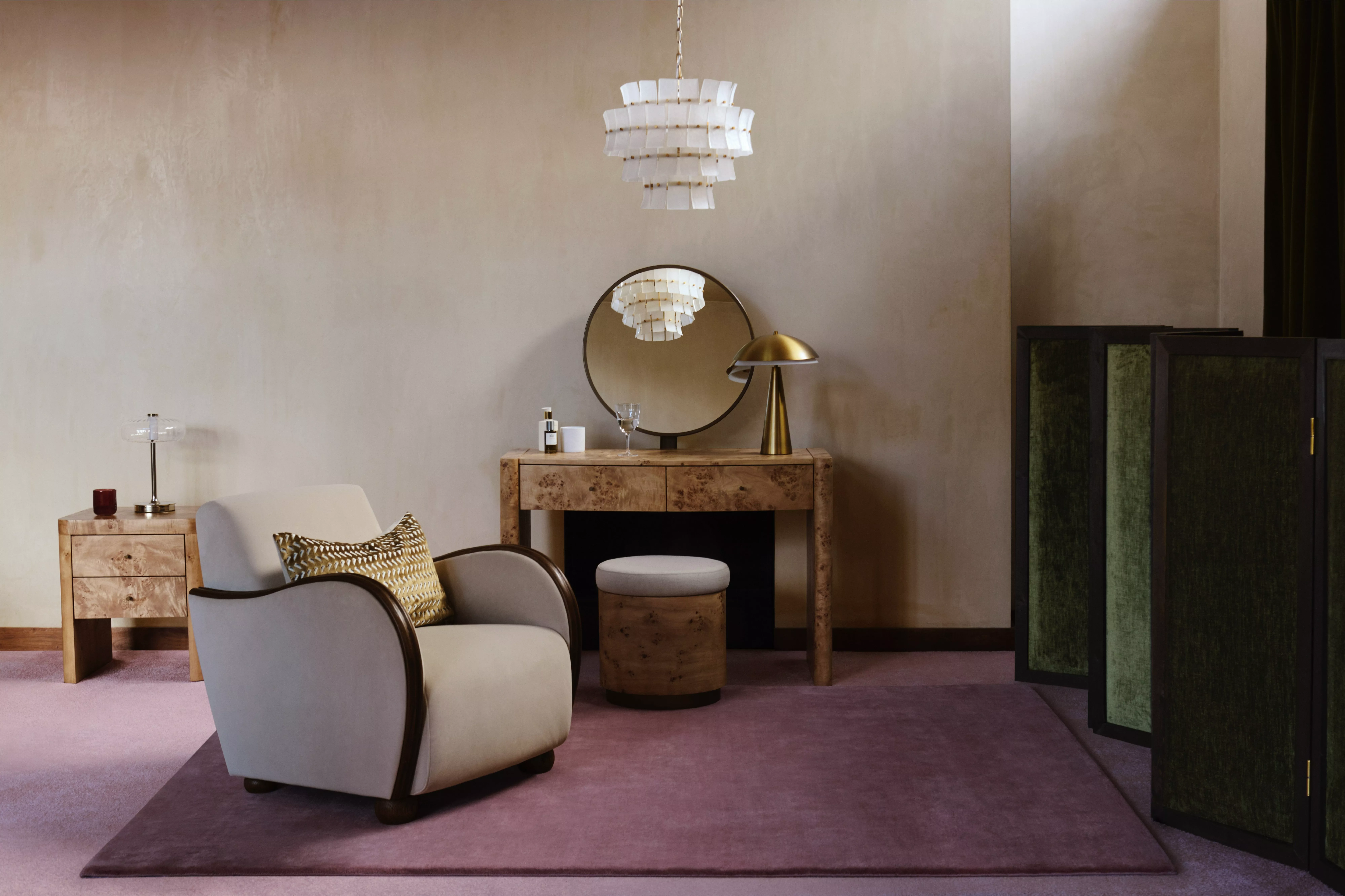 Modern living room with velvet armchair, burl wood console, brass lamp, pendant light and green screen divider