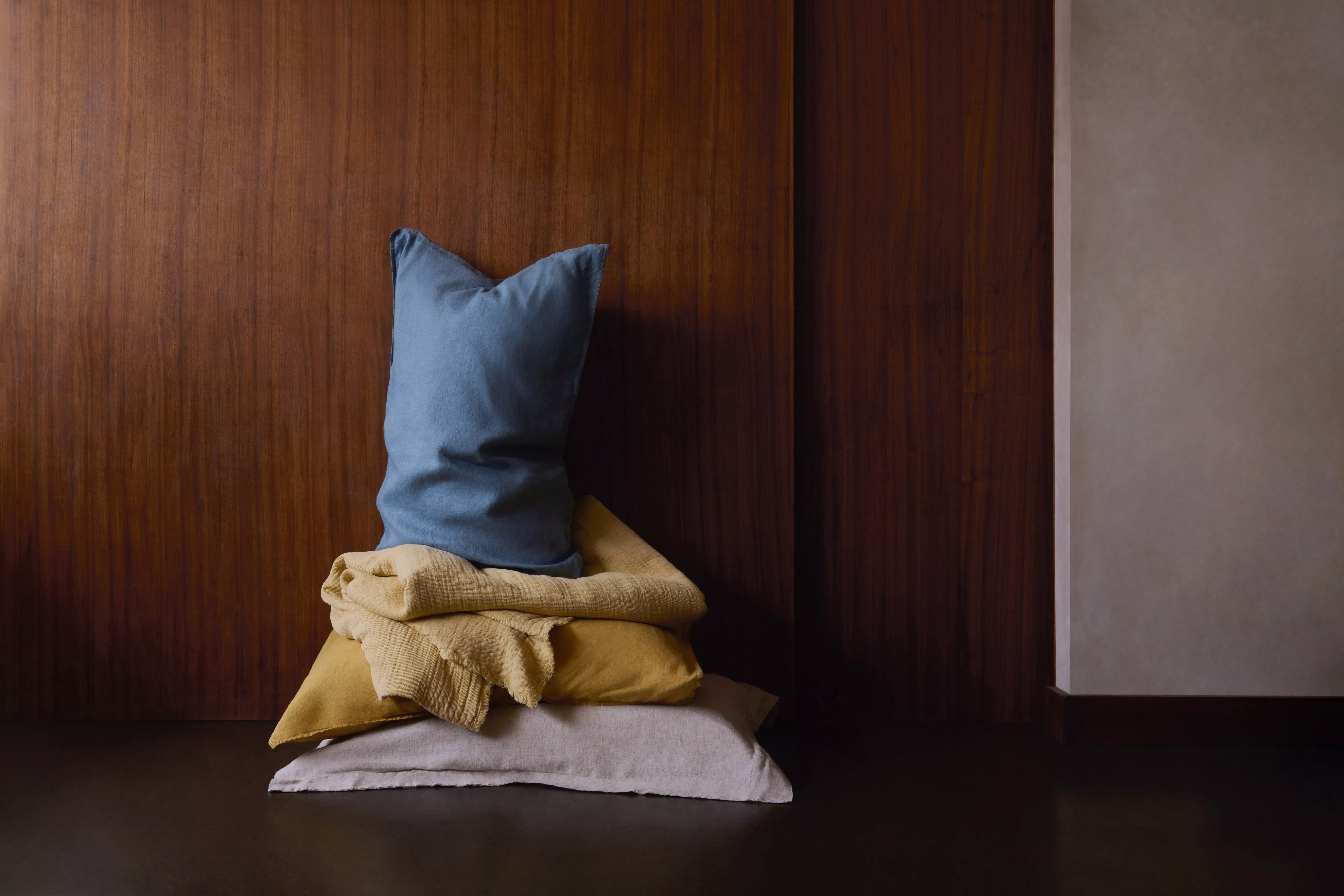 Cosy modern bedroom with blue bedding, mustard cushion, tray with mug, and patterned rug in soft light