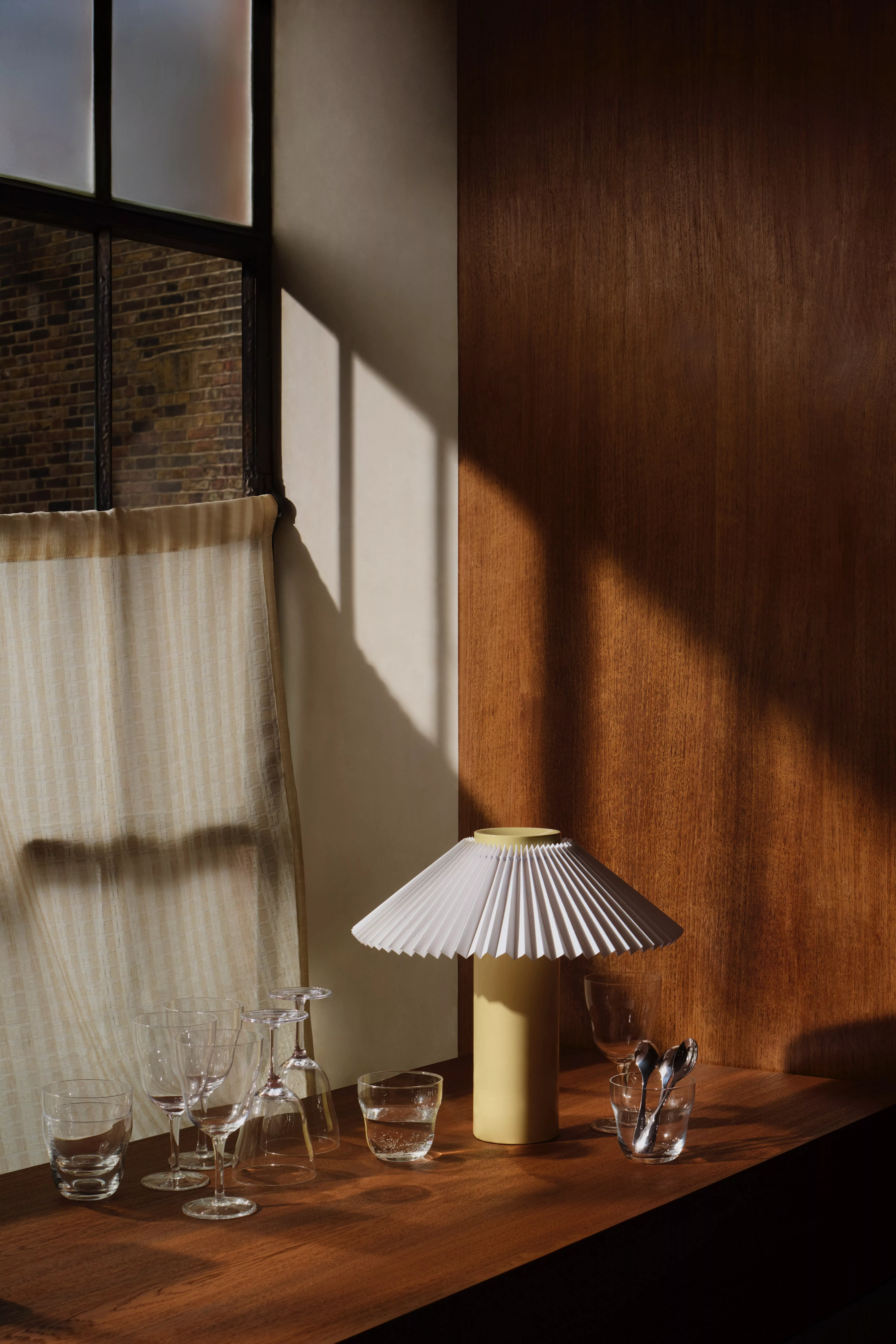 Floral patterned curtains on a metal pole framing a white sash window in a cosy rustic living room with beams