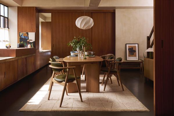 Mid-century modern dining room with wooden table, green chairs, pendant light and warm wood panelling