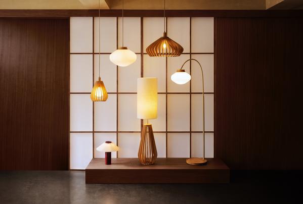 Modern pendant and floor lamps with warm wooden shades, styled on a shelf against a Japanese shoji screen backdrop