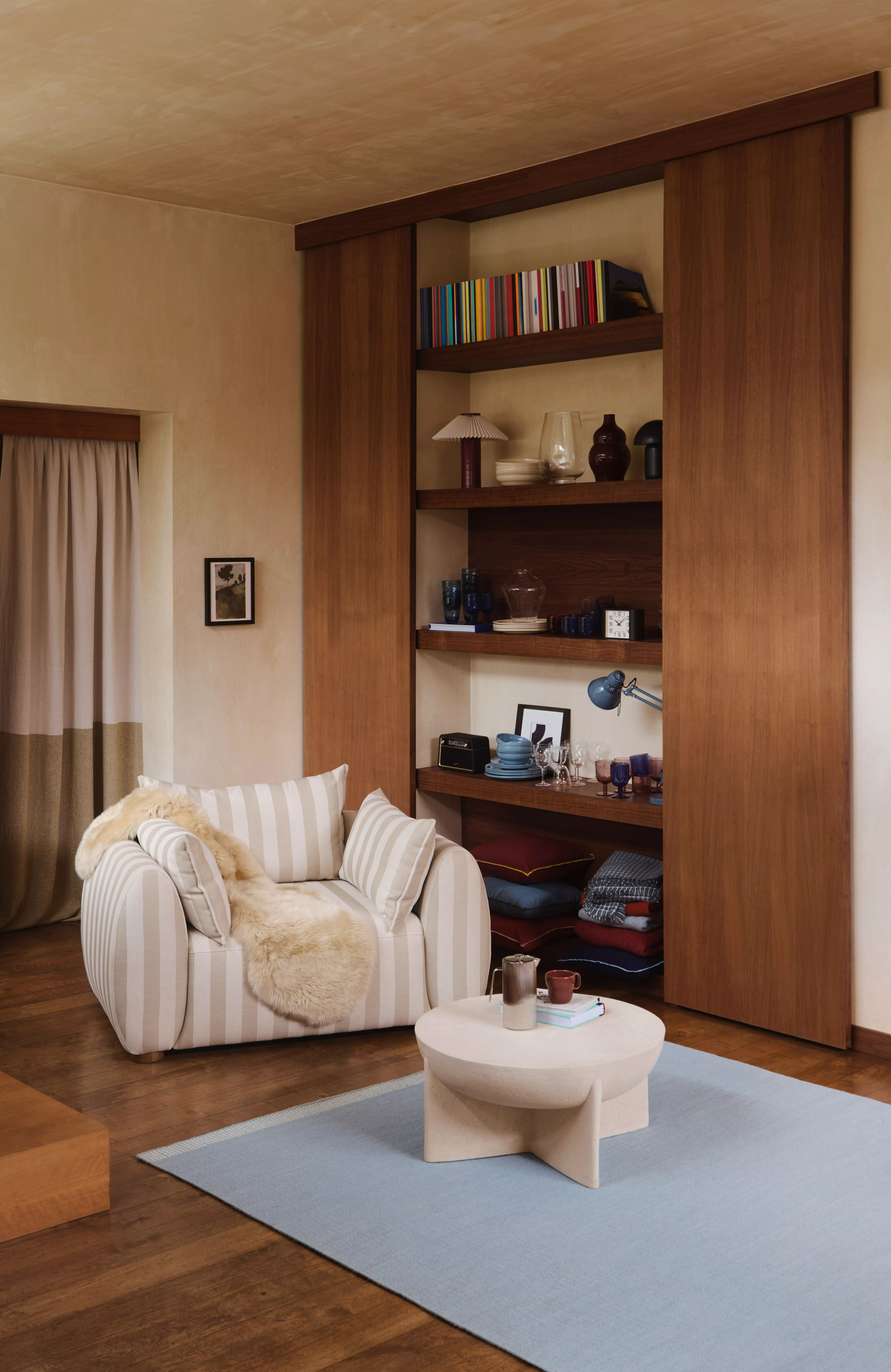 Mustard armchair with navy cushions, dark blue curtains and floral Roman blind in a modern living room interior
