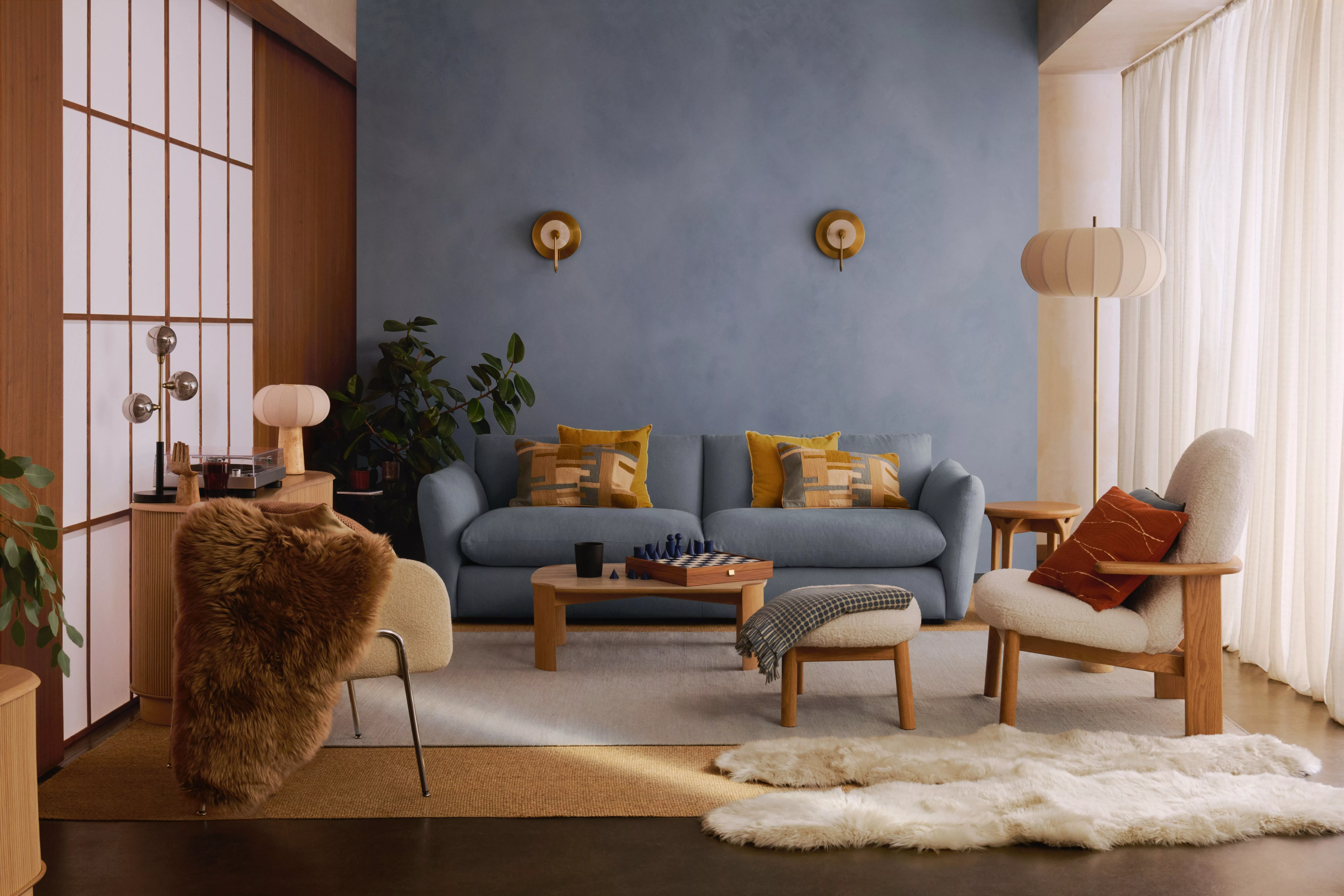 Modern living room with blue sofa, wood accents, cosy armchair, floor lamp and soft neutral textiles