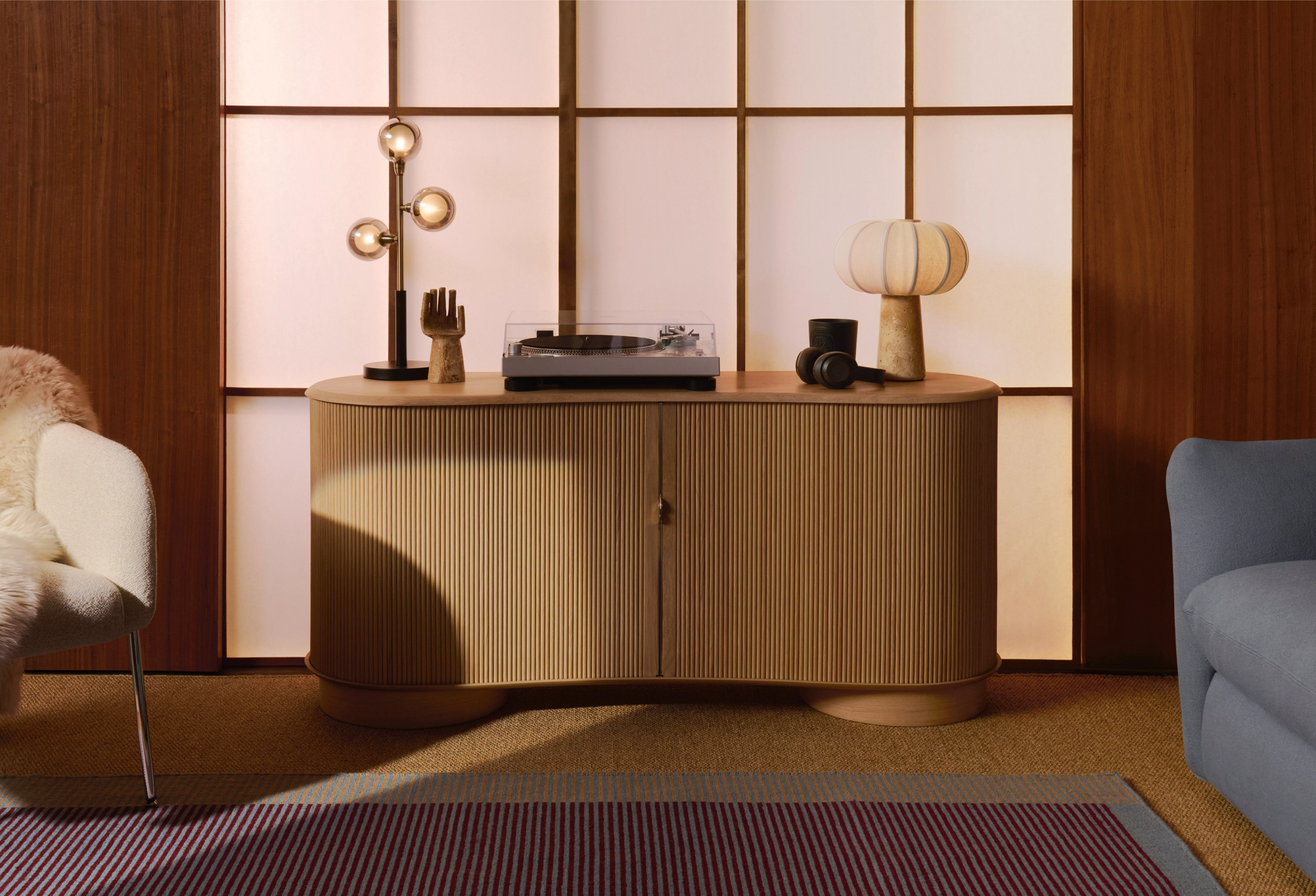 Mid-century modern interior with a wooden sideboard, abstract art, houseplants, and a turntable on display.
