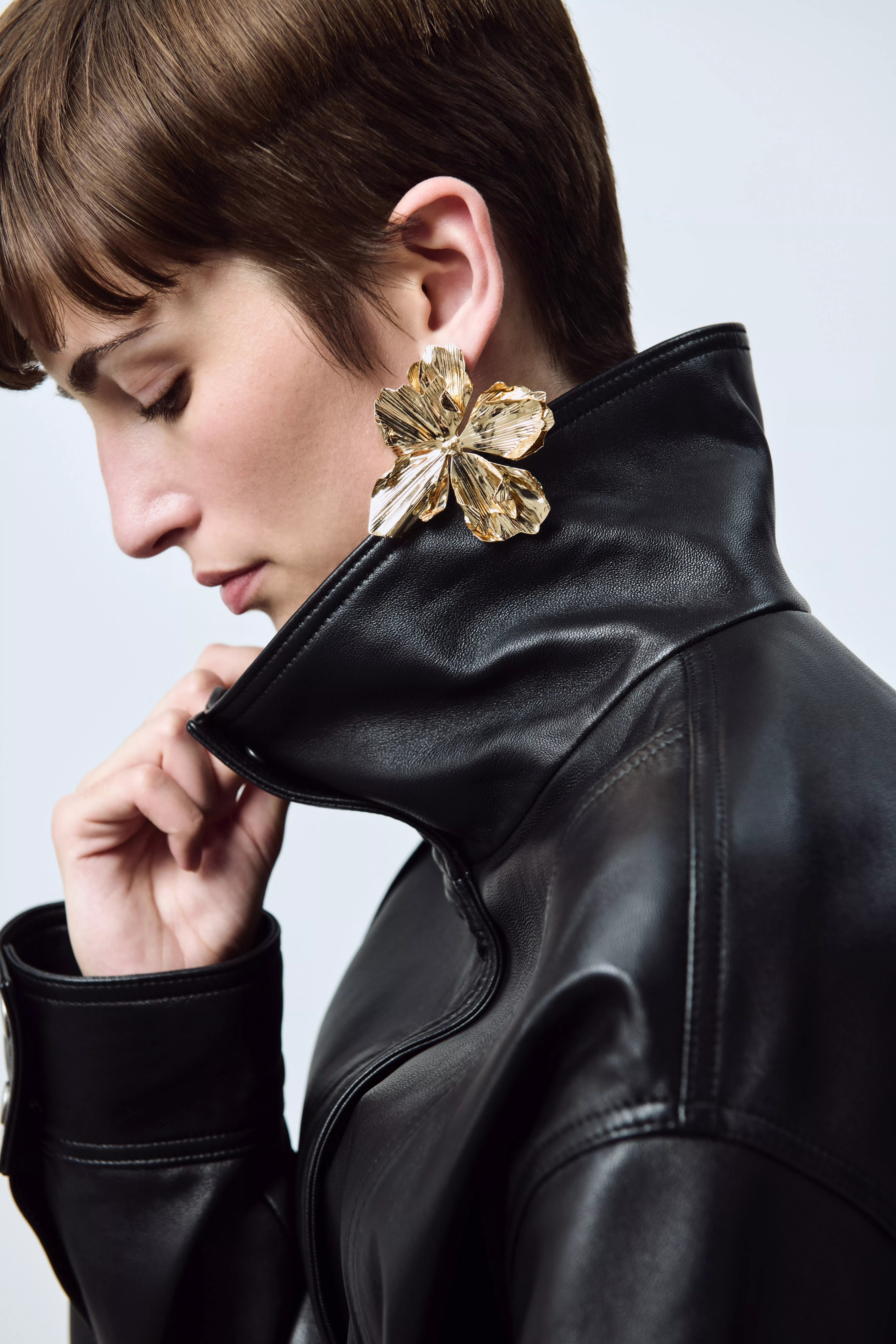 Elegant gold hoop earrings with a twisted design, reflecting light beautifully against a plain background.