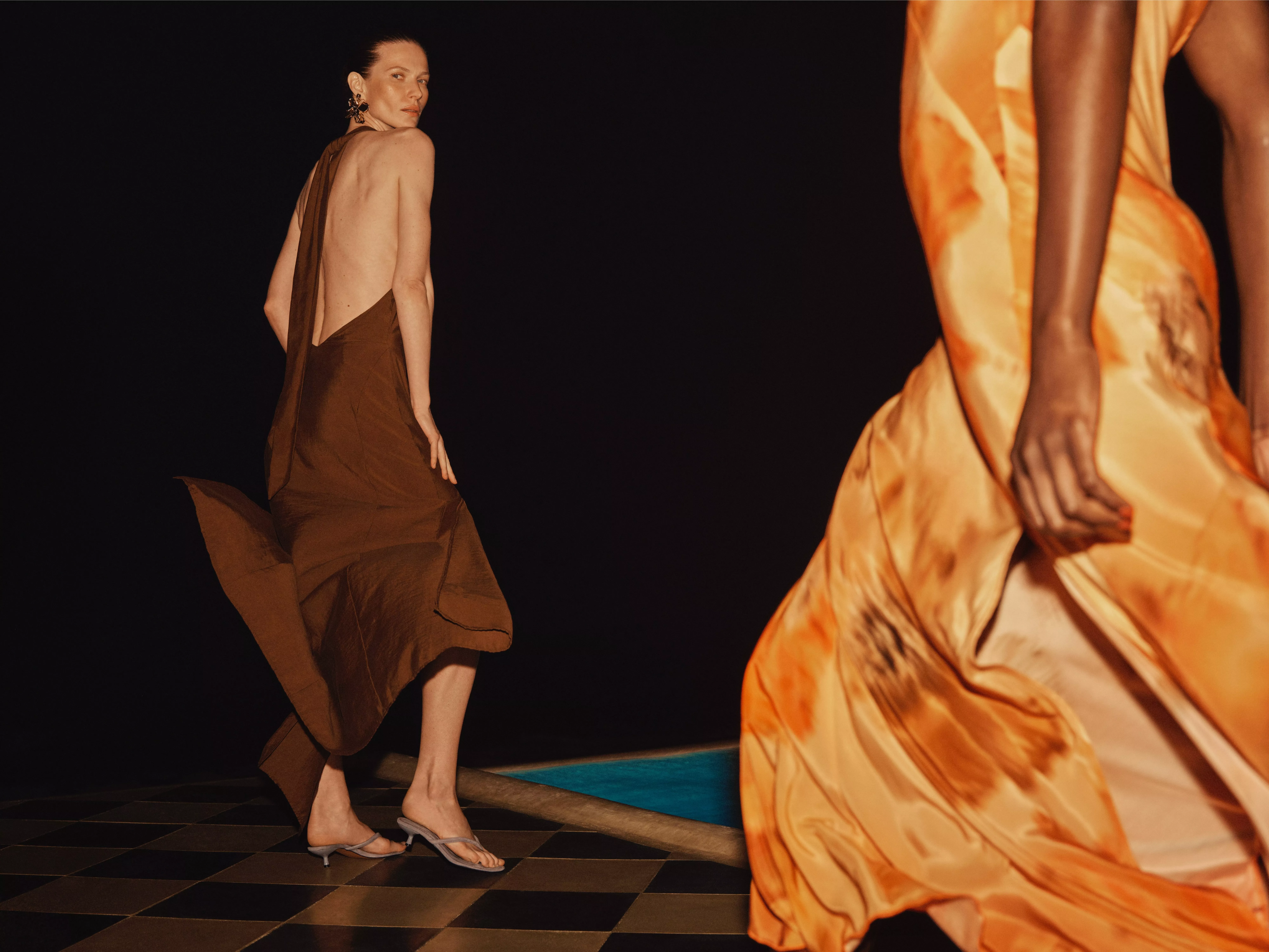 Models showcase elegant evening dresses, one in brown with an open back and another in a vibrant orange pattern.