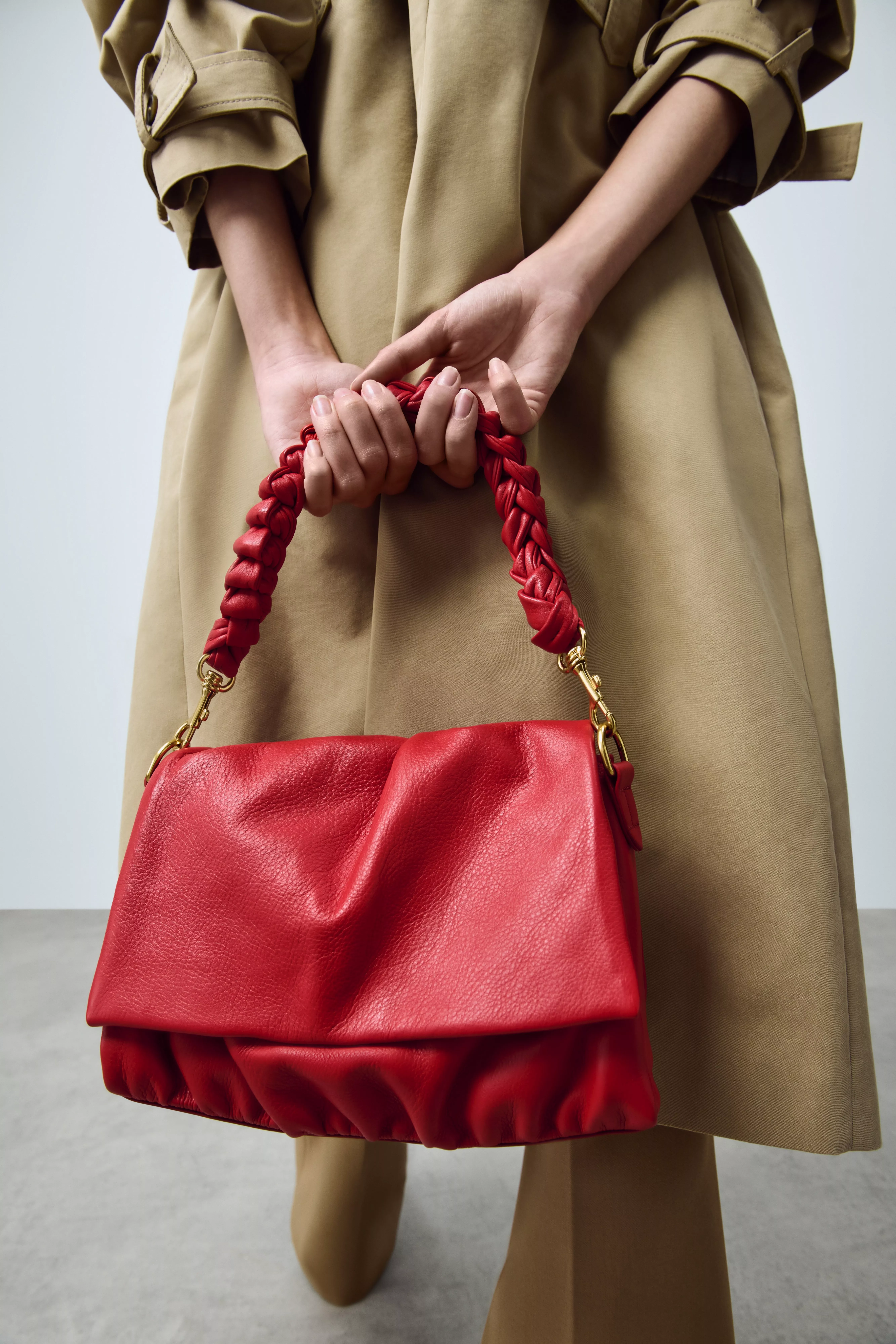Woman carrying a red leather ruched flapover crossbody bag