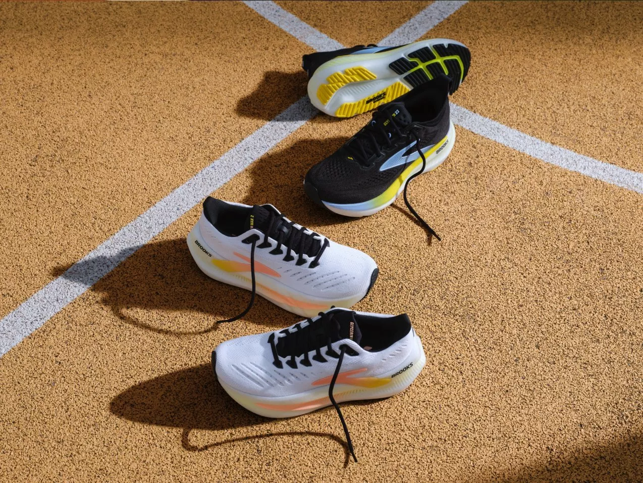 Brooks running shoes on an athletics track, black and white trainers with laces, top-down product shot