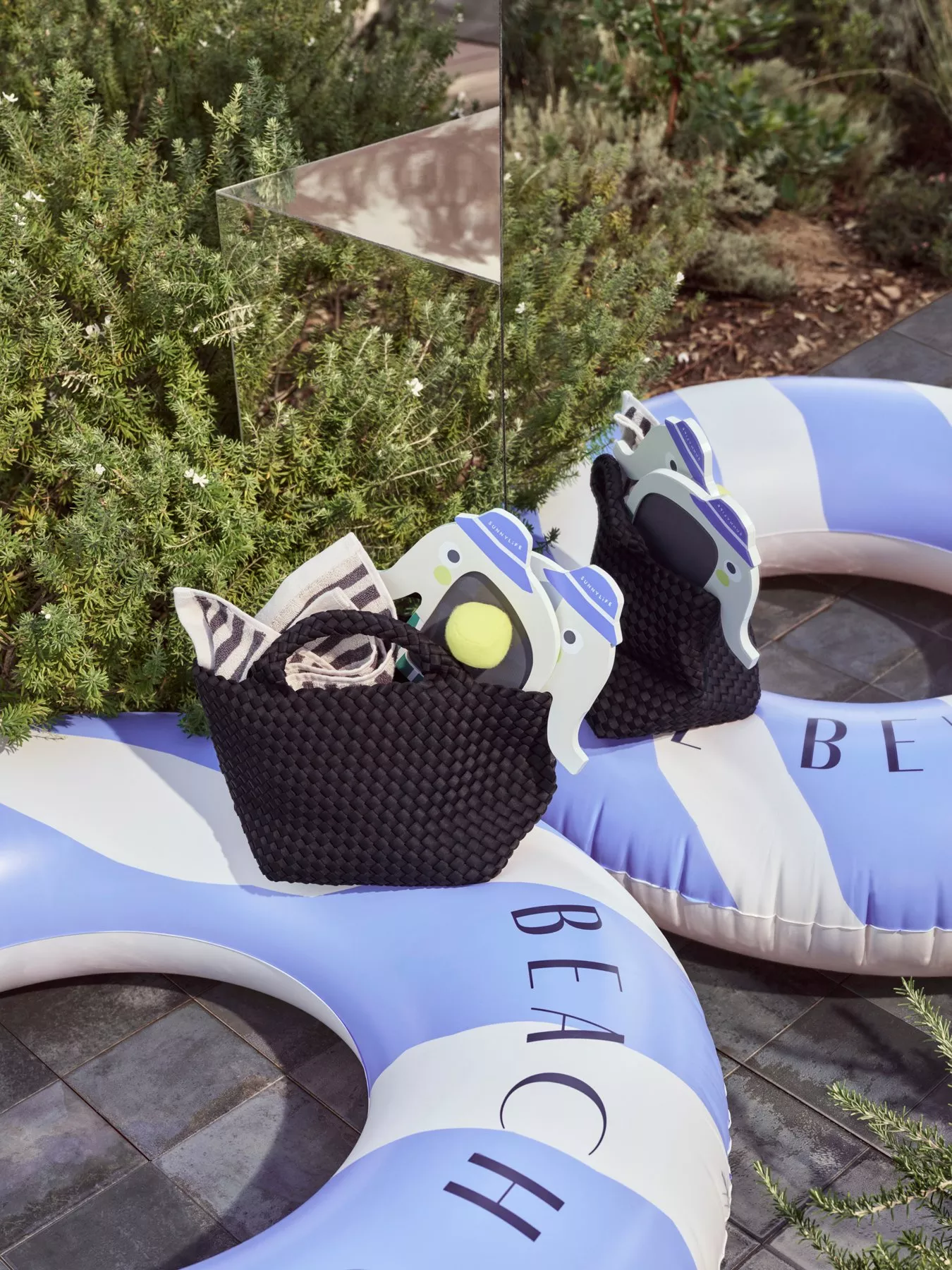 A handbag with a towel and beach bats on top of a pool float