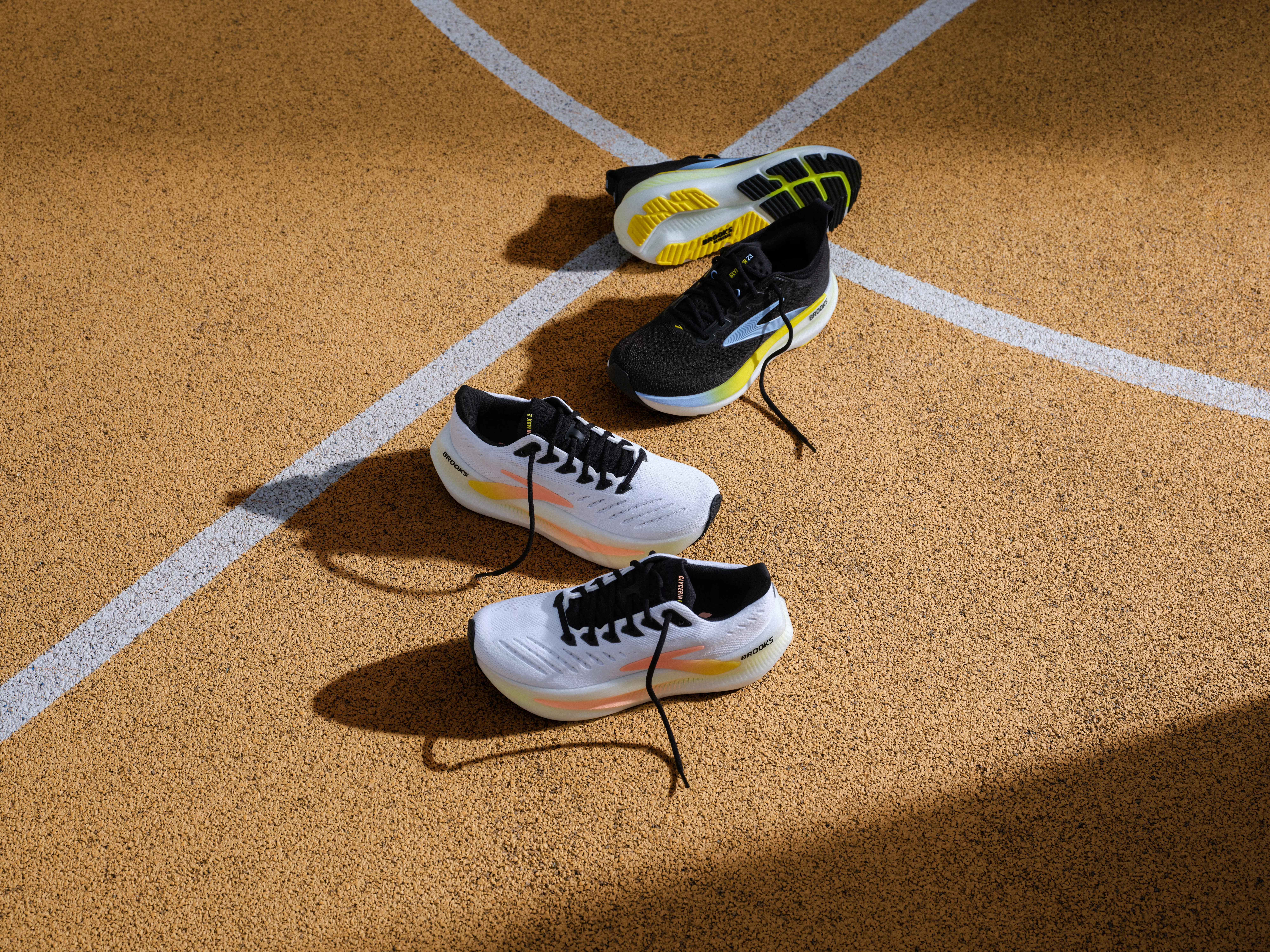 Running shoes on an athletics track, black and white trainers with laces loose on lane markings