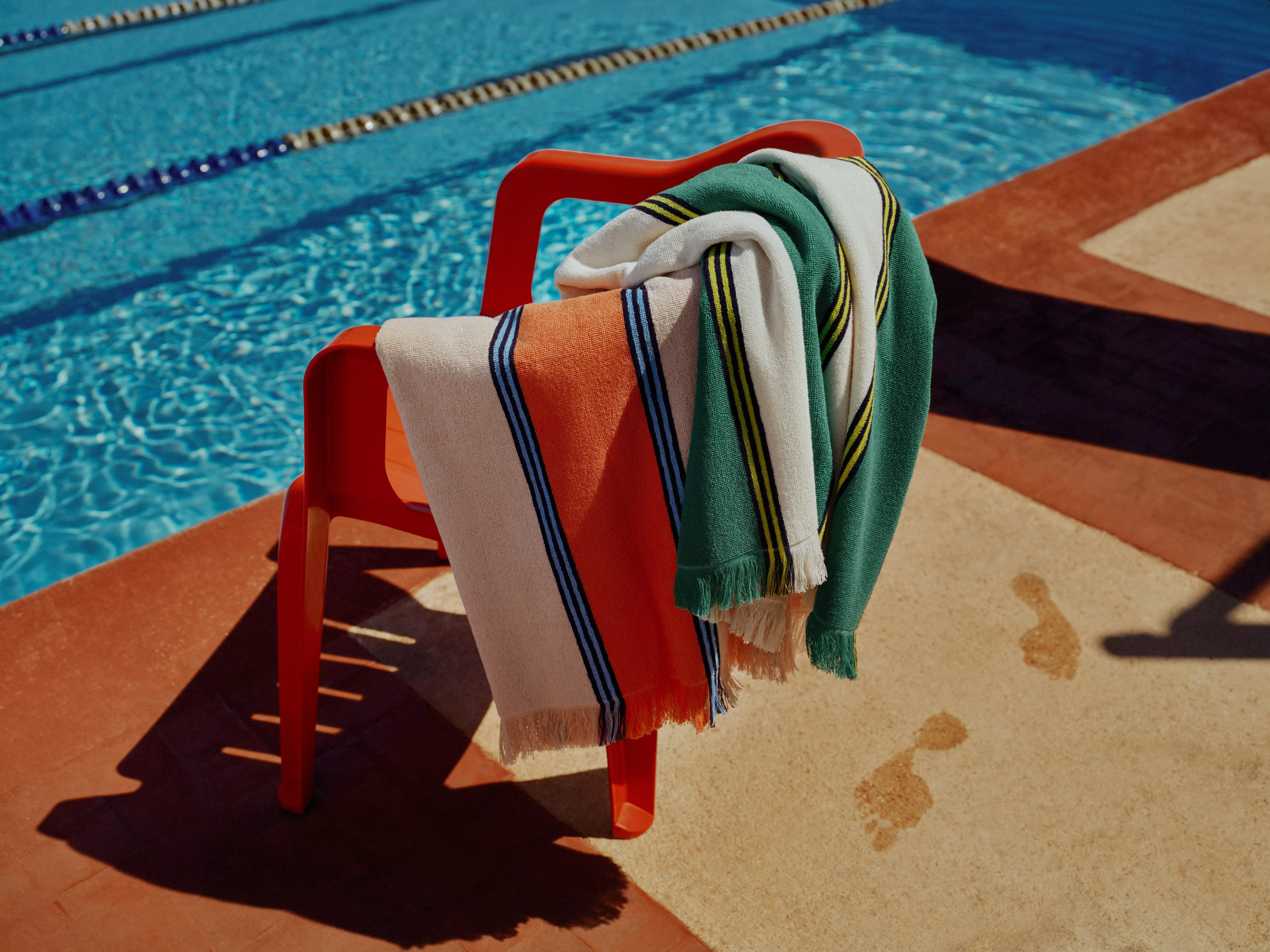 Multi-colour striped beach towel hanging over a red chair