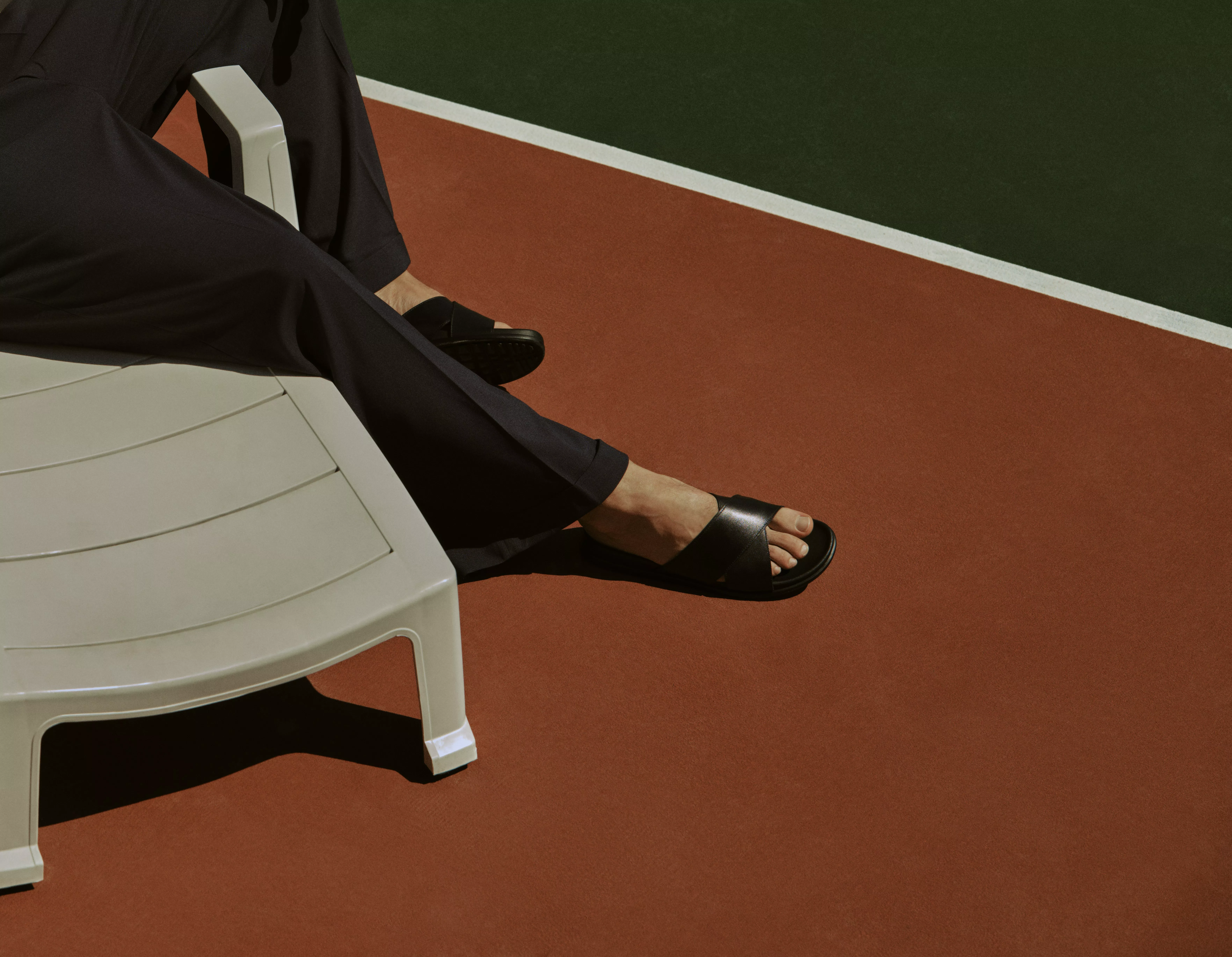 Man sitting on a sunlounger wearing black leather sandals
