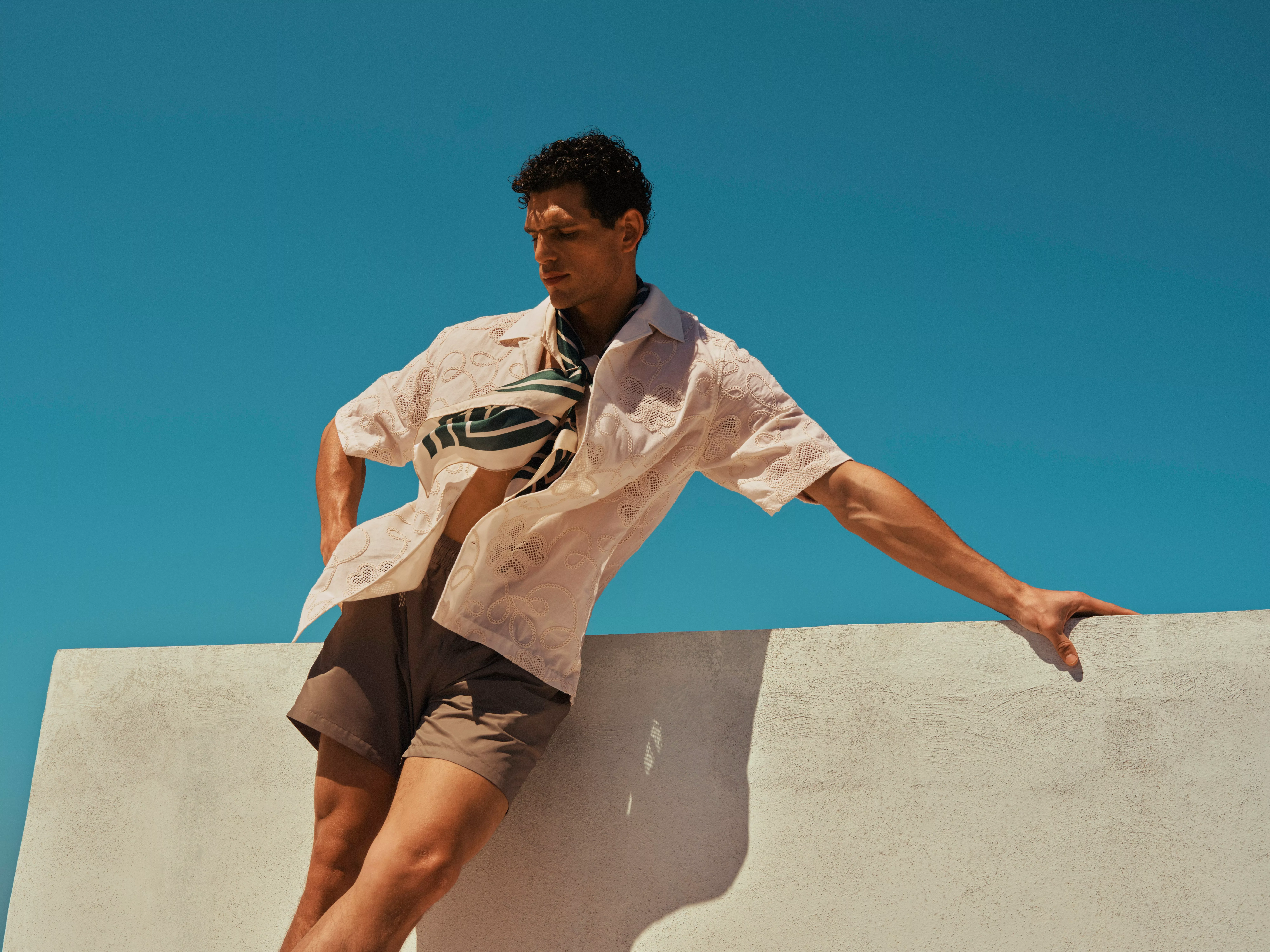 Man wearing a khaki shorts with shirt and scarf