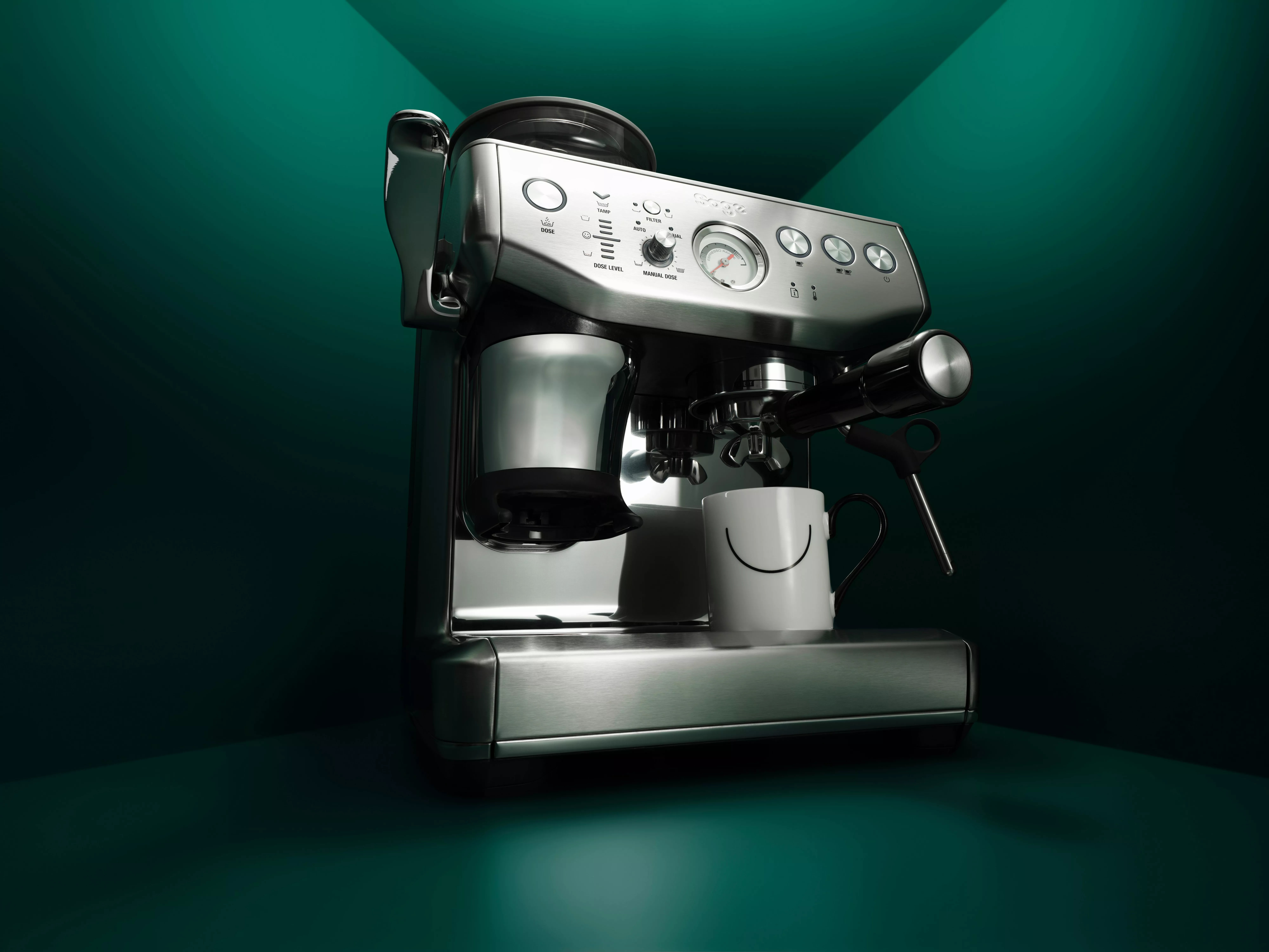 Stainless steel espresso coffee machine with portafilter and steam wand, cup underneath, on dark green background