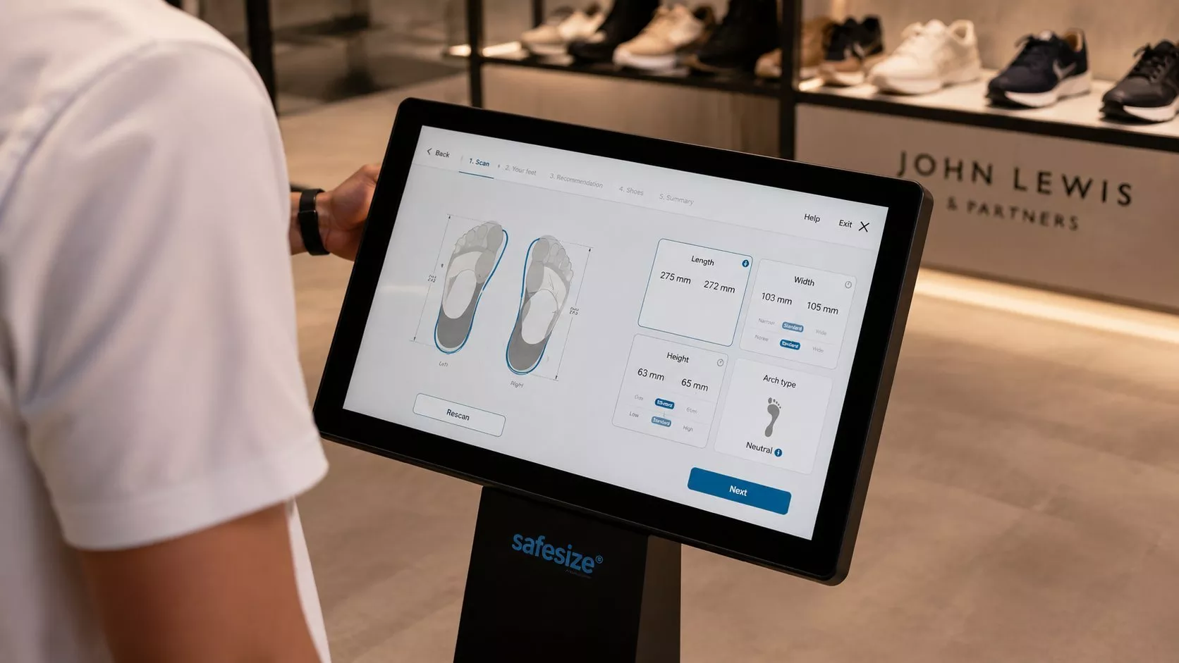 Customer using SafeSize foot scanning kiosk in John Lewis shoe department for accurate shoe fit sizing
