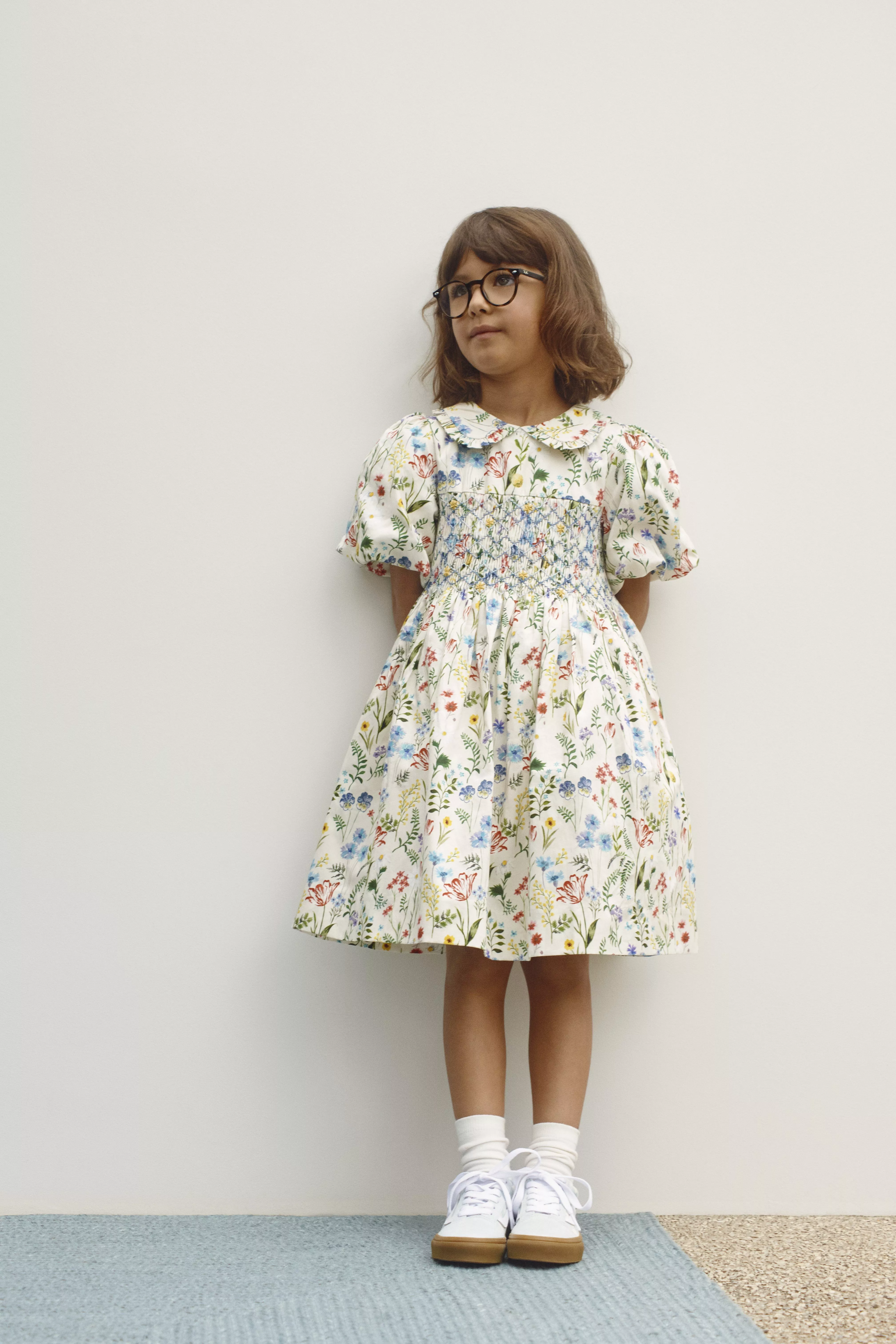 Girl wearing a cream floral dress and white trainers