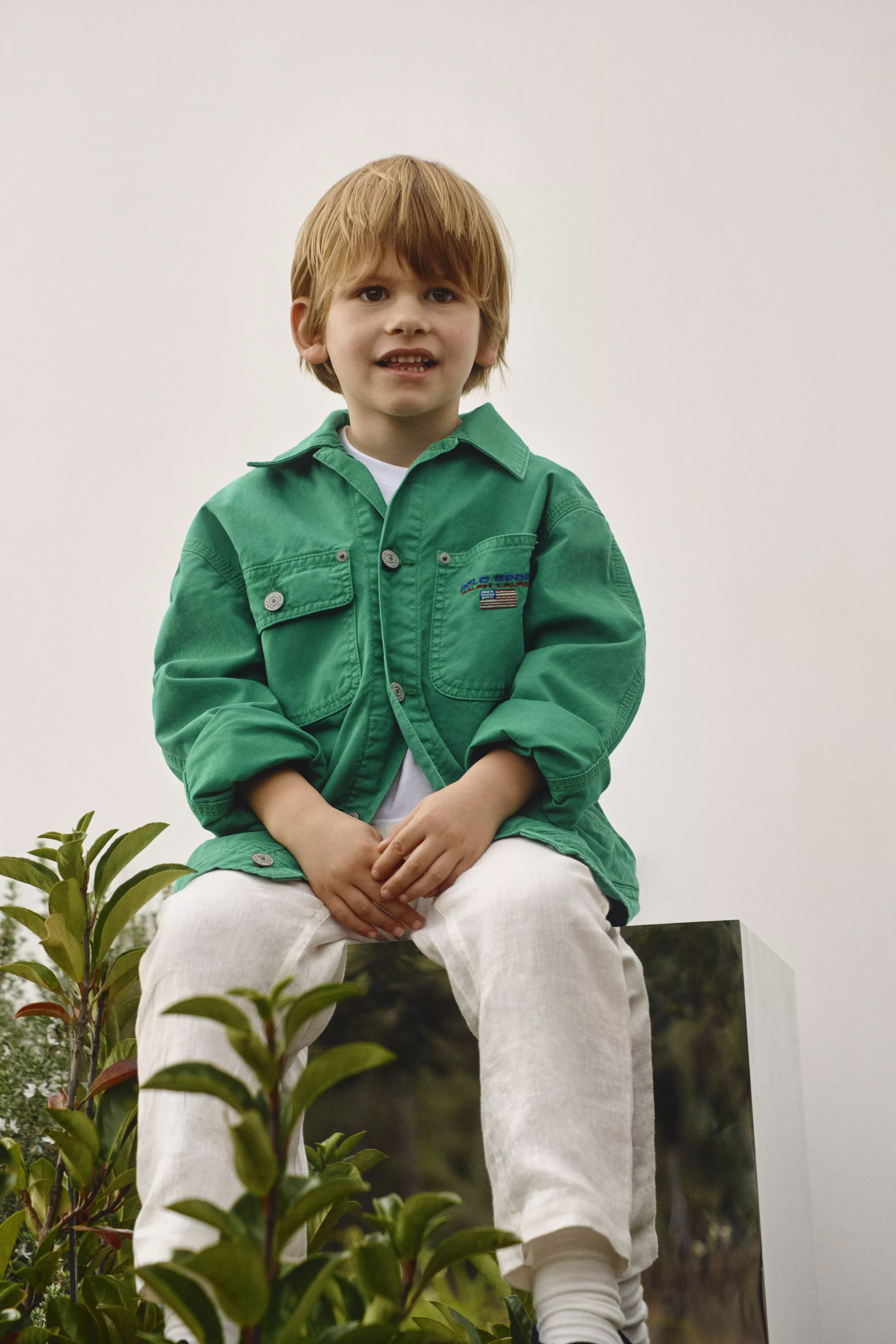 Boy in a green jacket and white trousers 