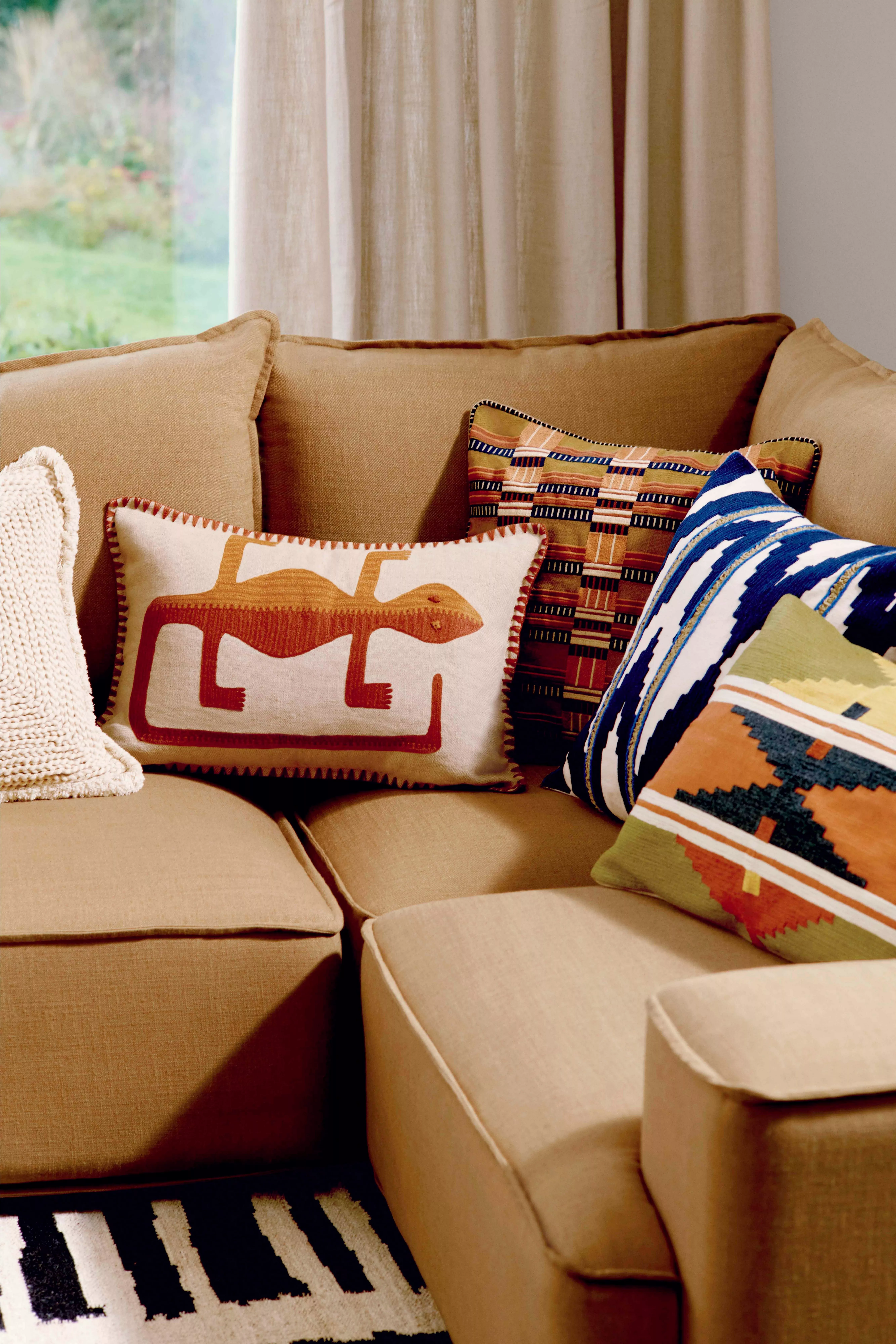 Cosy beige sofa adorned with vibrant patterned cushions, enhancing the room's warm and inviting atmosphere.