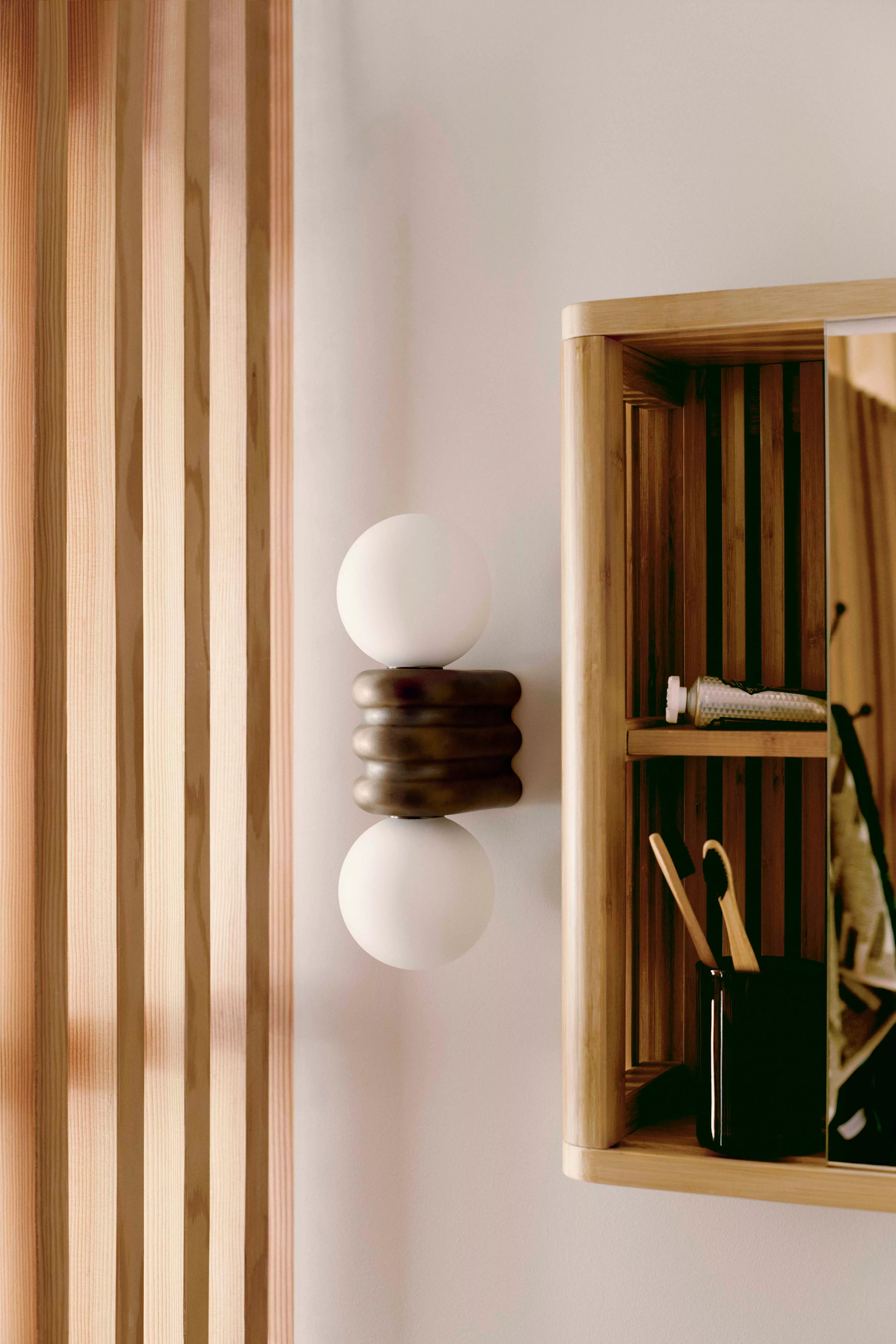 A modern table lamp with a textured beige shade and a glossy green ceramic base on a glass-topped table.