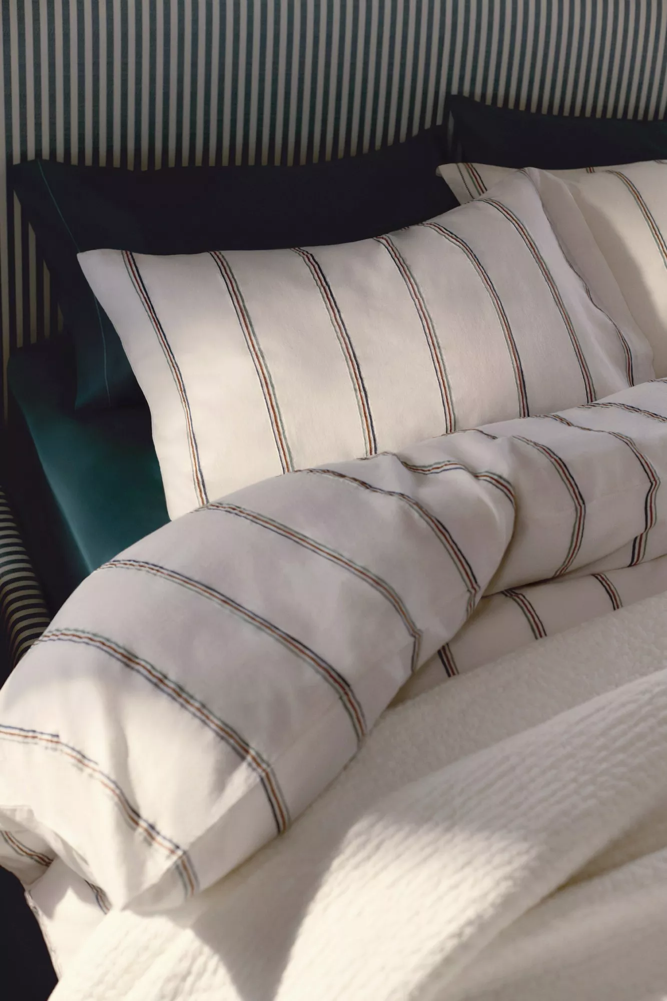 Striped bedding set with white and dark pillowcases on a bed, complemented by a striped headboard.