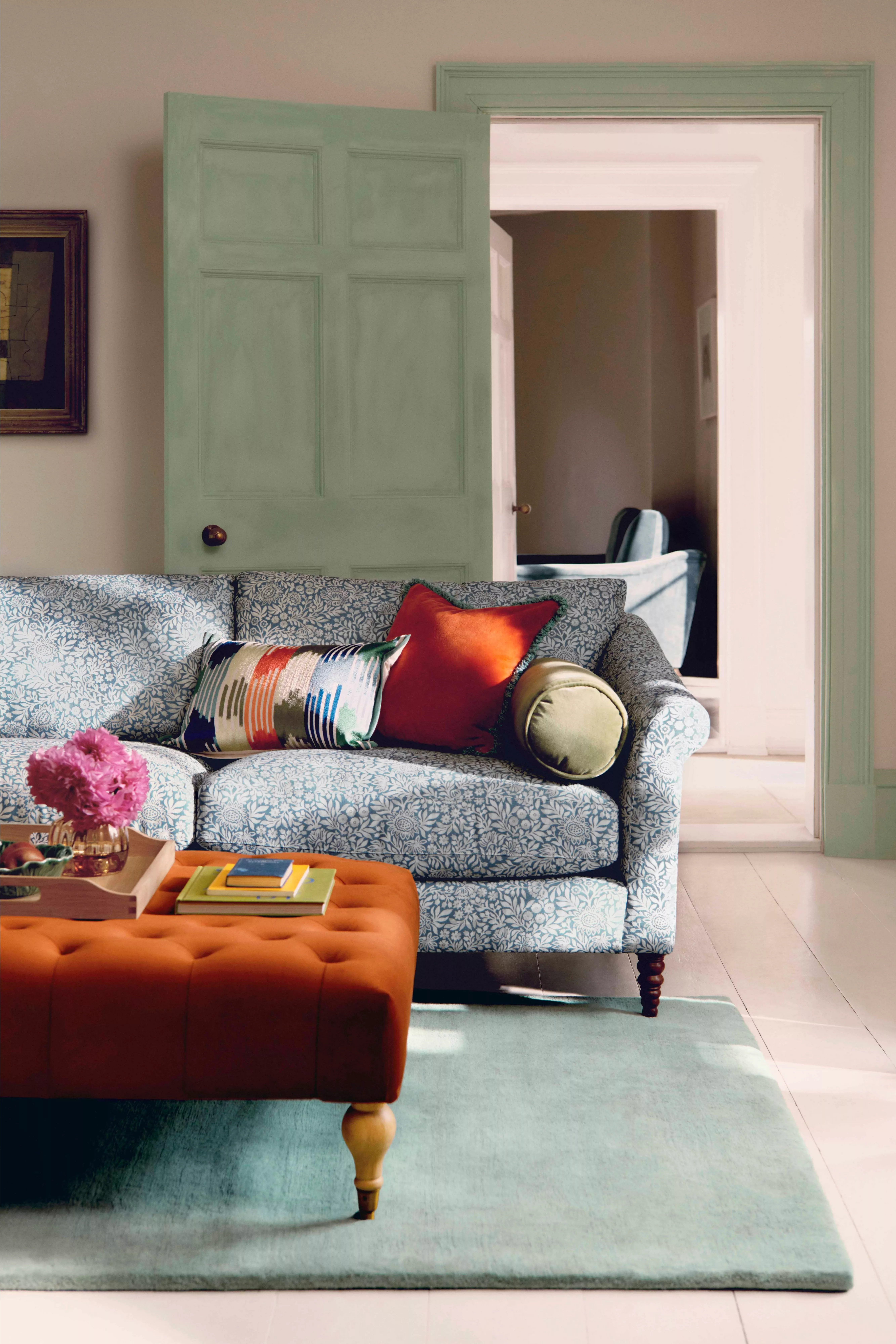 Stylish interior with a green armchair, modern pendant light, and large window overlooking lush garden scenery.