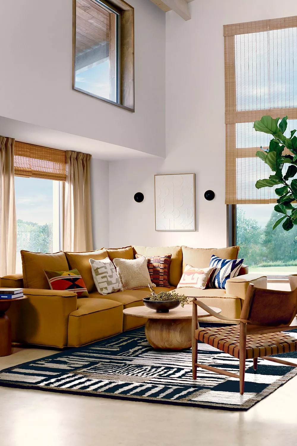 Modern living room with a mustard sectional sofa, patterned cushions, and a wooden coffee table on a geometric rug.
