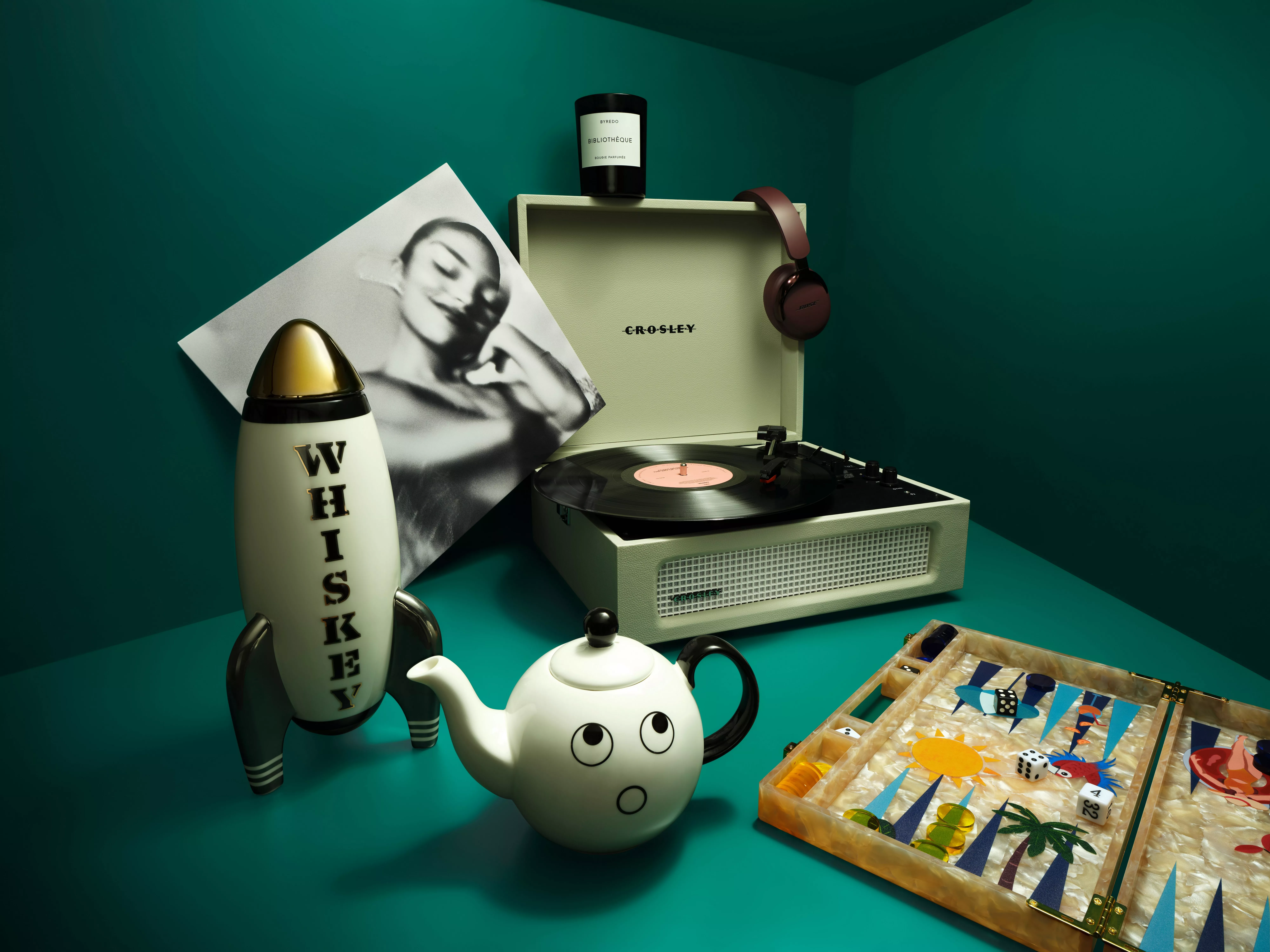 Still life with Crosley record player, vinyl, whisky rocket, teapot and tabletop game in teal room