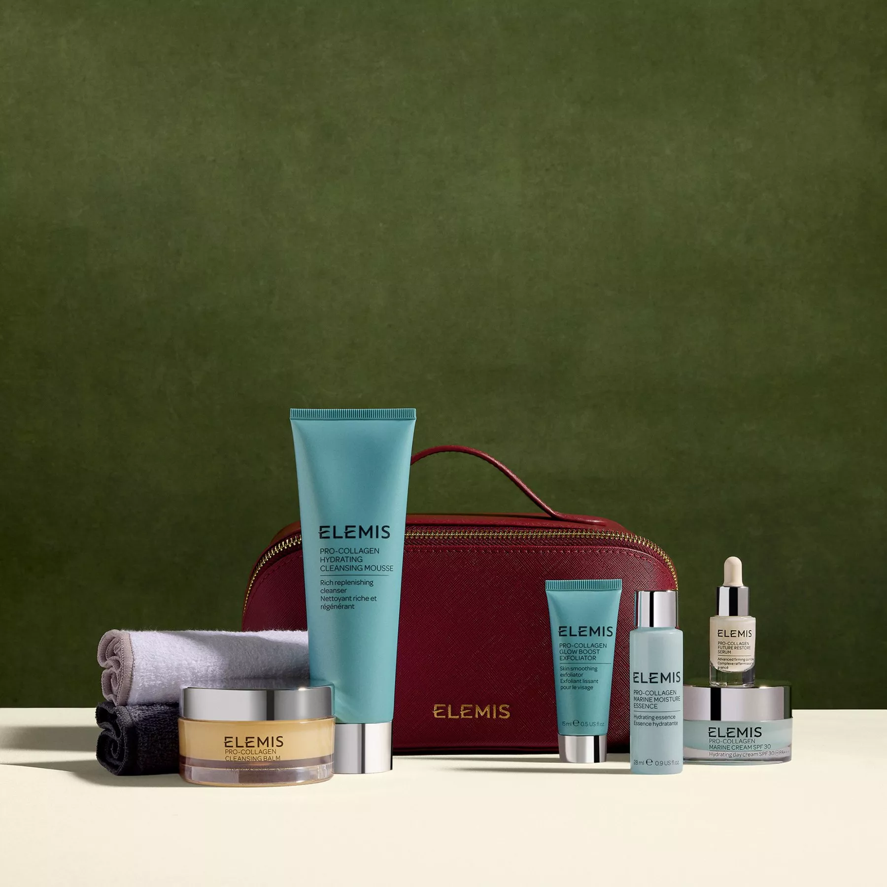 ELEMIS Pro-Collagen skincare set with cleansing mousse, creams, serums and red wash bag on beige surface