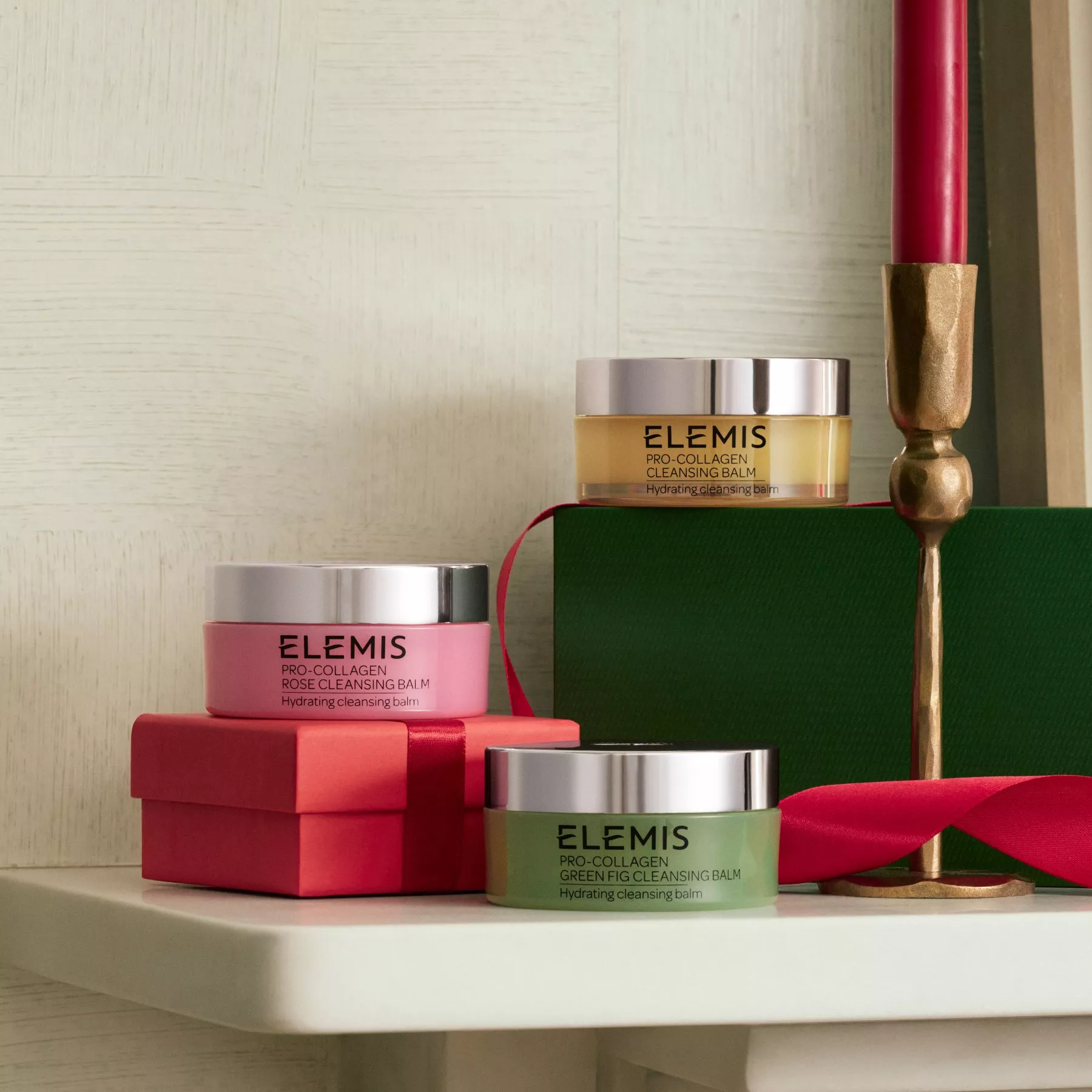 ELEMIS Pro-Collagen cleansing balm gift set jars on festive boxes with red candle, luxury skincare display