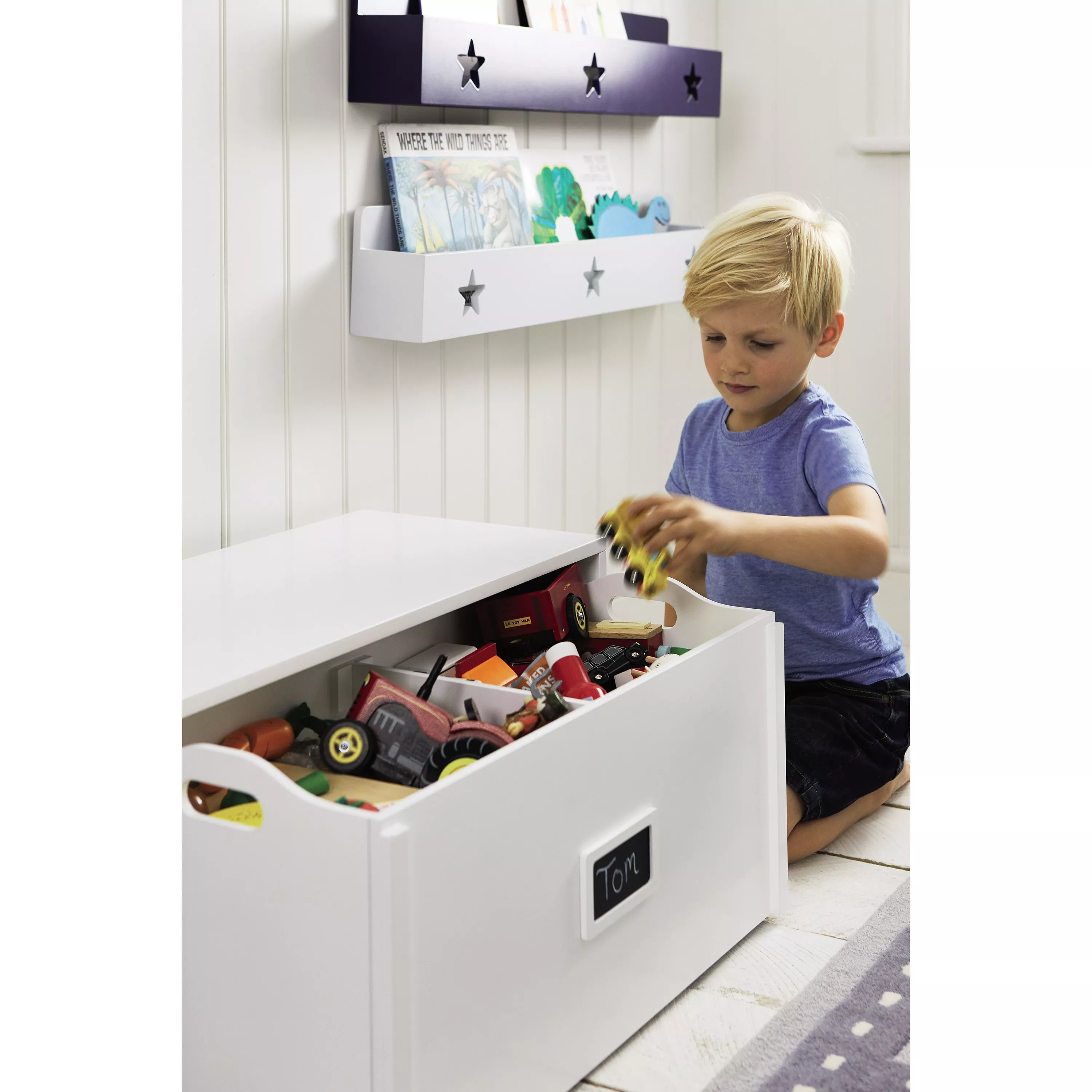 Child playing with toy cars beside white wooden toy box and wall book rack, ideal kids bedroom storage furniture