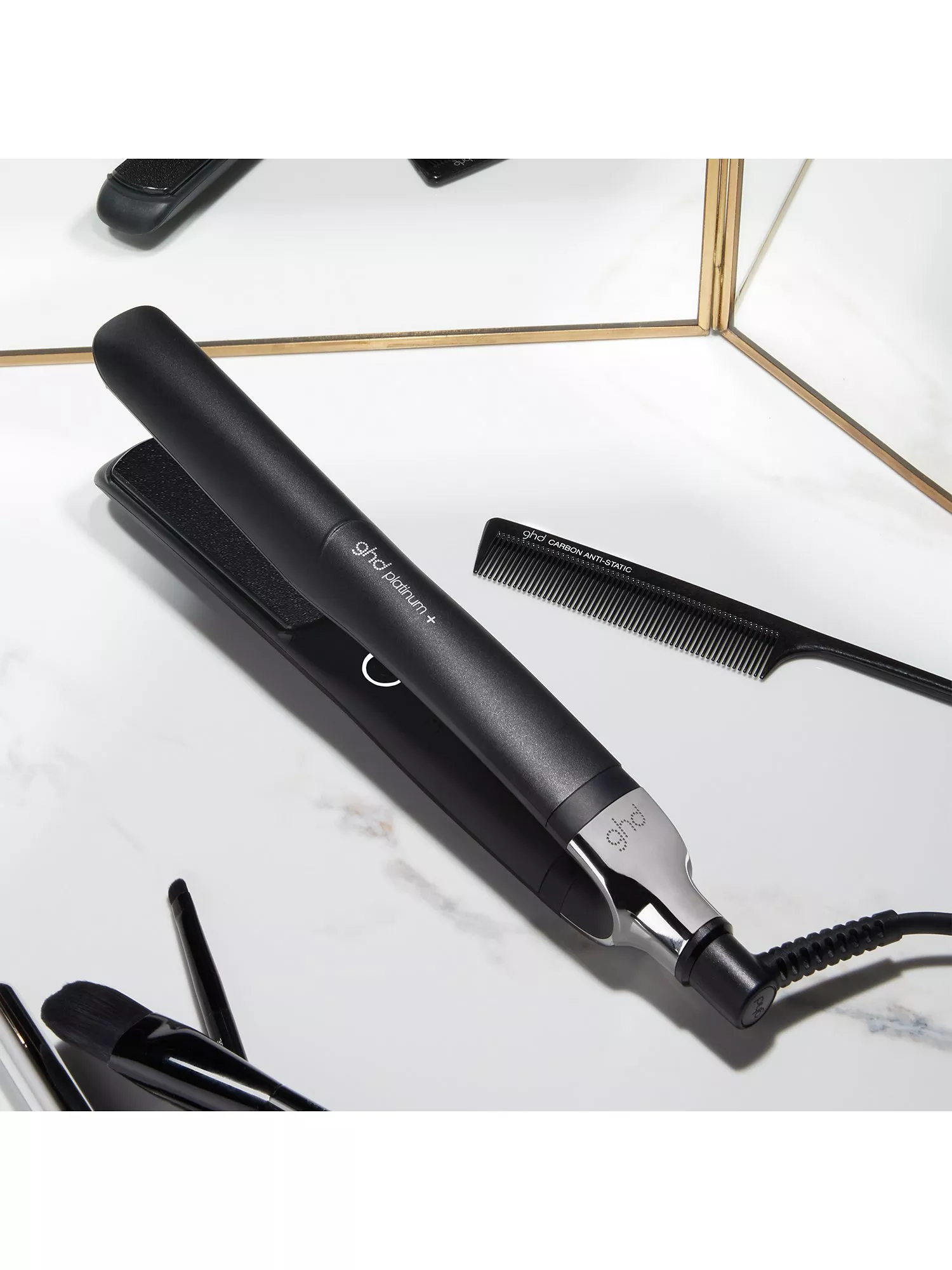GHD Platinum+ hair straightener on marble countertop with carbon anti-static comb, salon styling tool flat lay