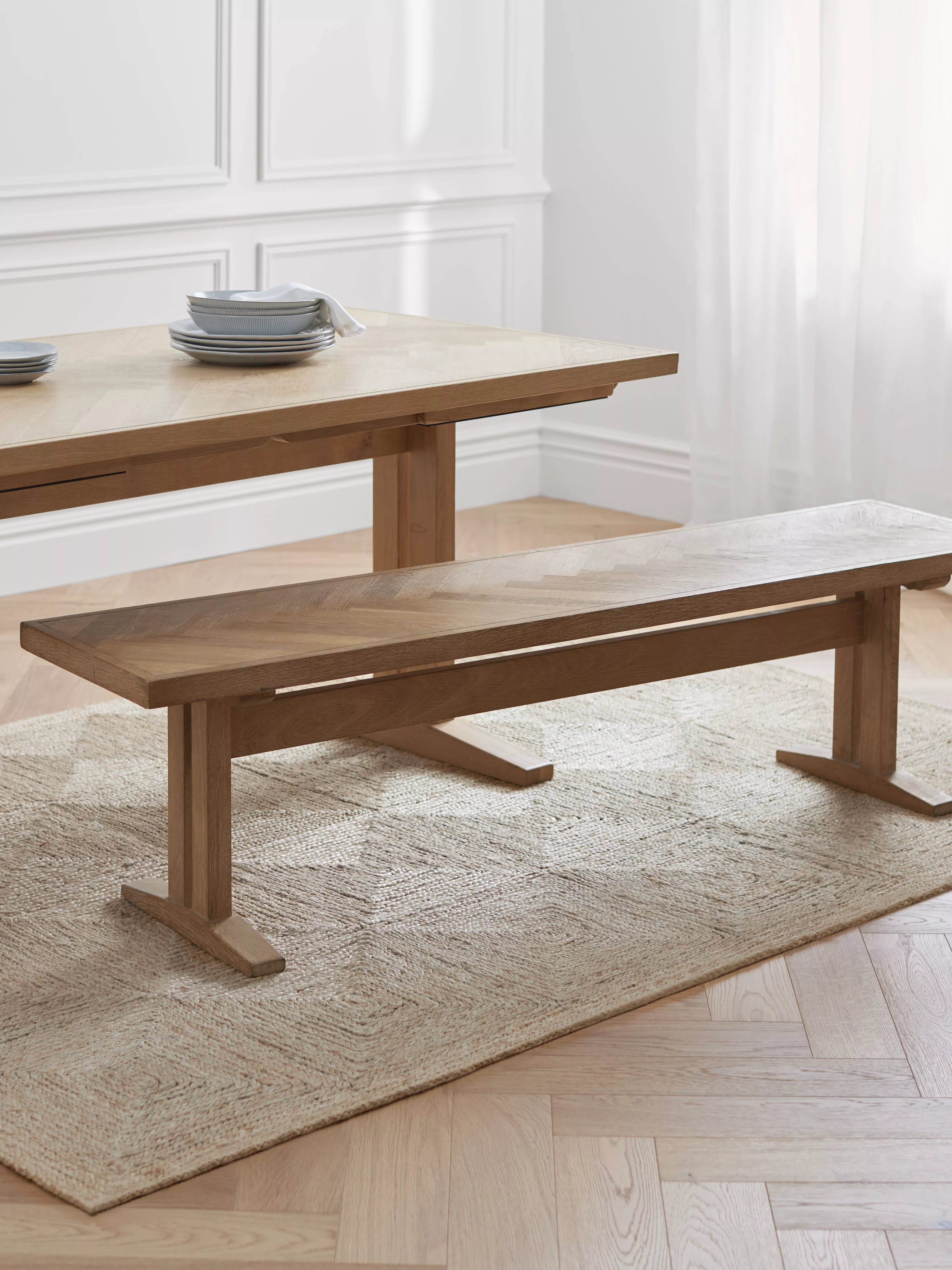 Solid oak dining bench with herringbone seat beside wooden table in bright, modern dining room interior