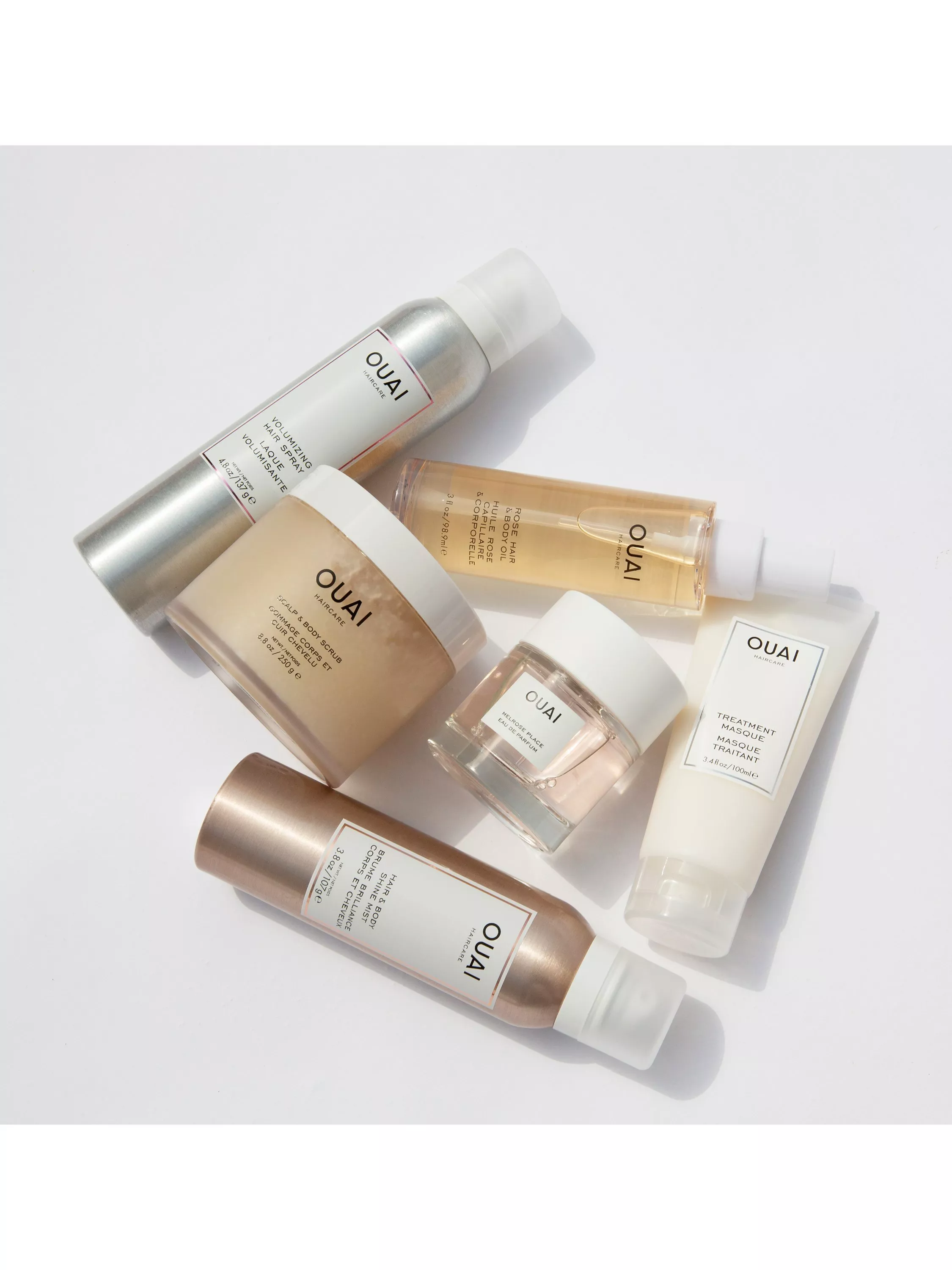 A collection of Ouai haircare products, including sprays, oils, and treatments, arranged on a light background.