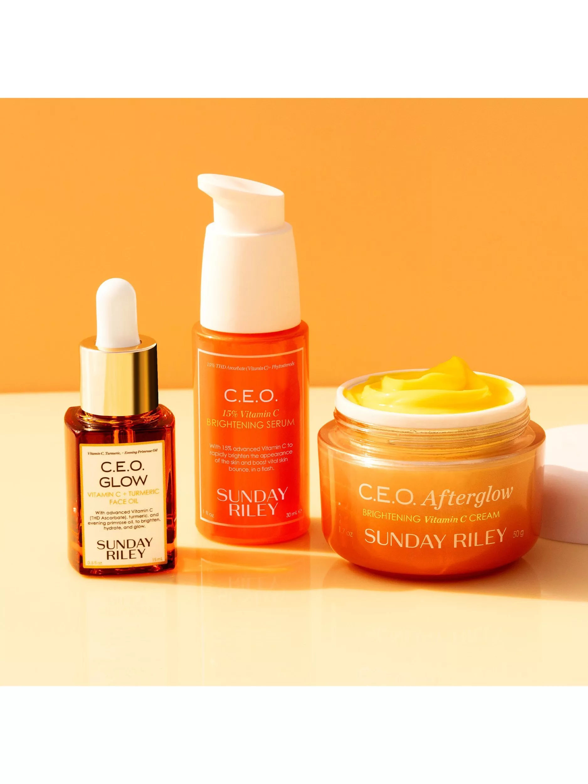 Sunday Riley C.E.O. vitamin C skincare set with face oil, brightening serum and Afterglow cream on orange backdrop