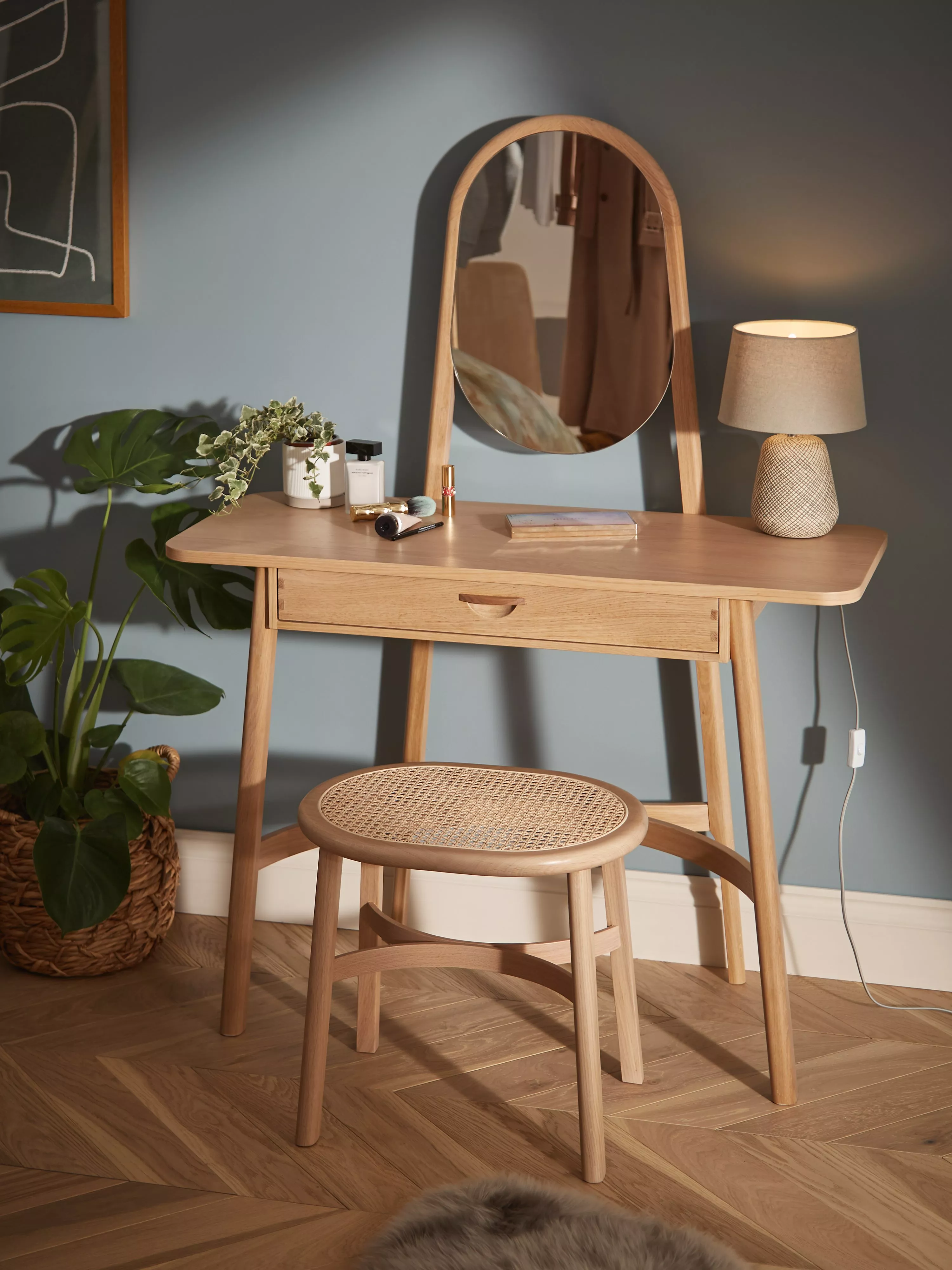 Scandinavian oak dressing table with mirror, stool and lamp, styled vanity setup with plants and cosmetics