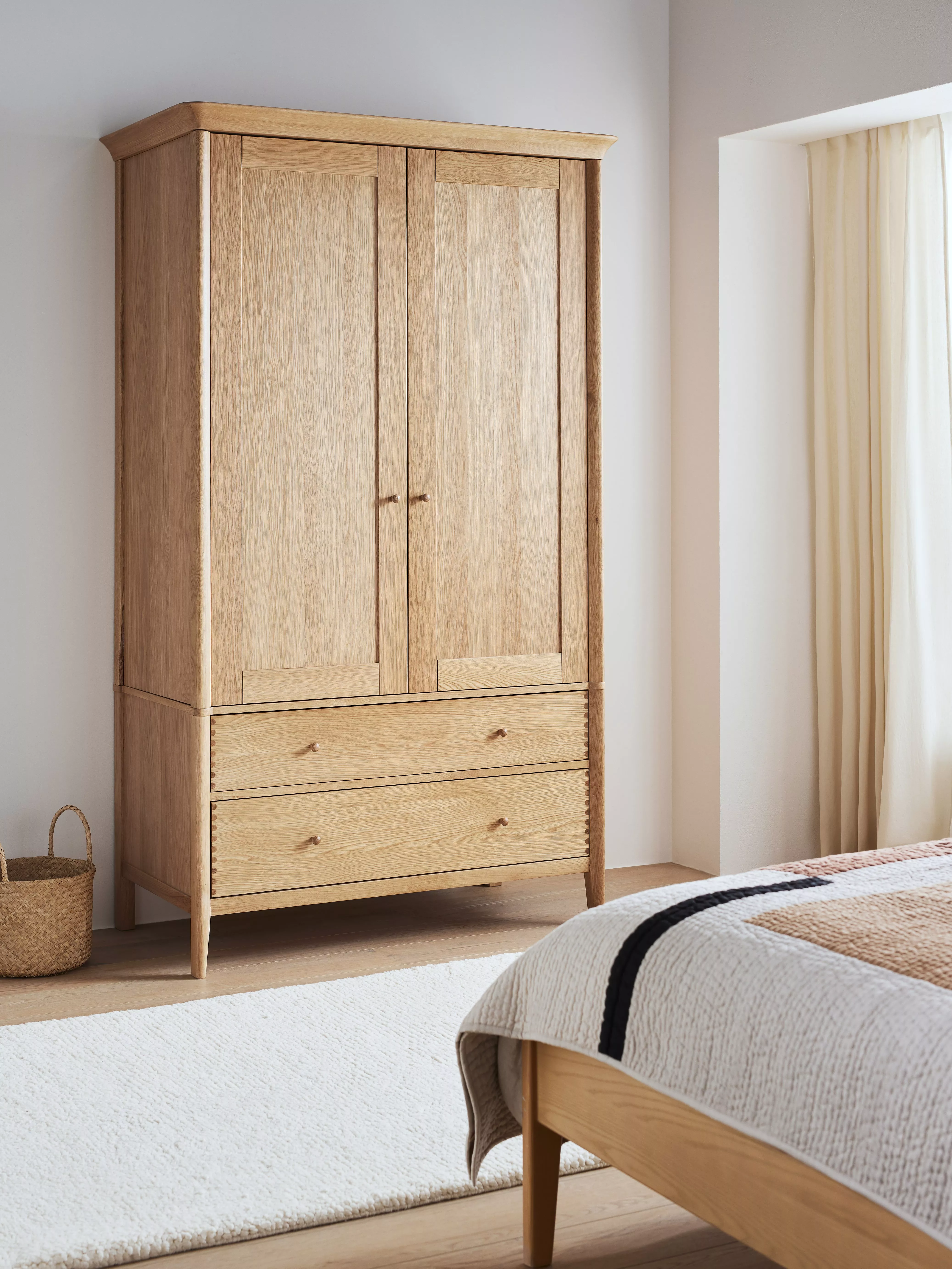 White painted double-door wardrobe with bottom drawer, styled in a modern bedroom with bedside table and lamp