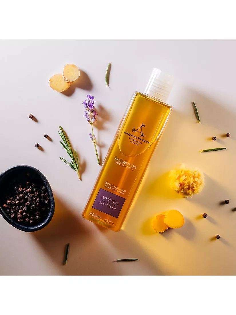 Aromatherapy Associates Muscle shower oil bottle with lavender, ginger, rosemary and peppercorns flat lay