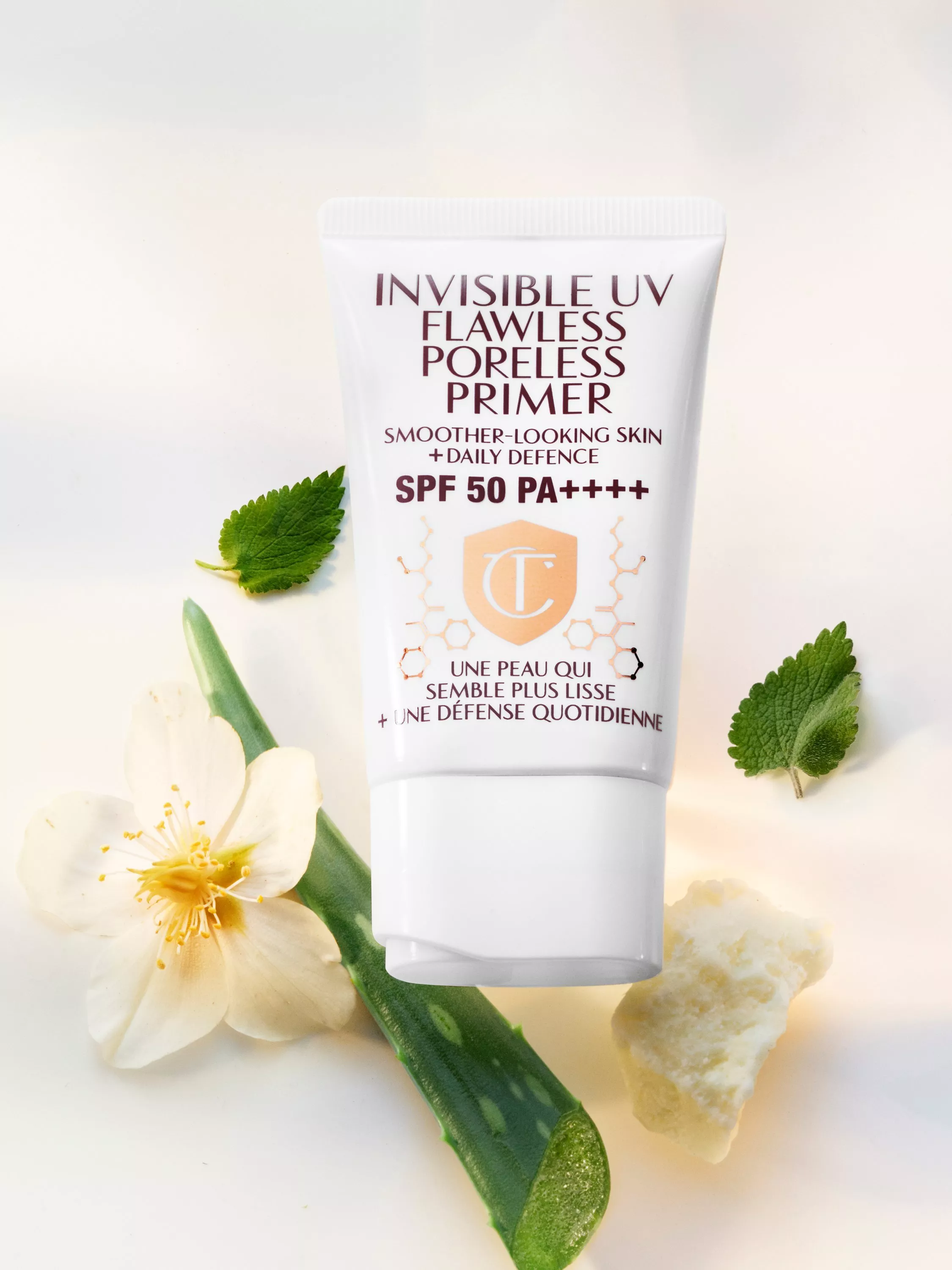 Invisible UV flawless poreless primer SPF 50 PA++++ tube with aloe vera, mint leaves and white flower on backdrop