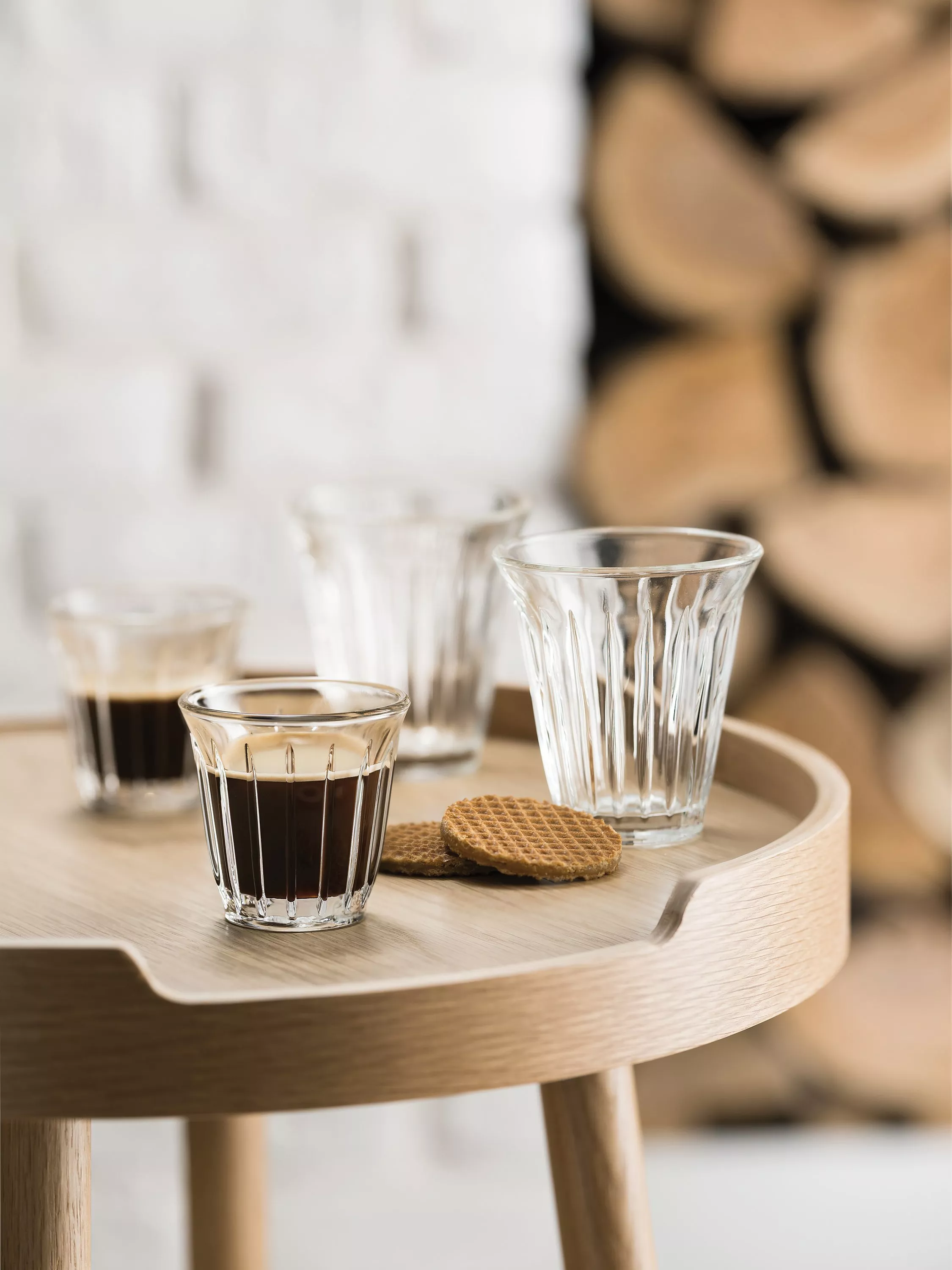 Stovetop moka pot on wooden tray with two white espresso cups and saucers, modern kitchen coffee setup